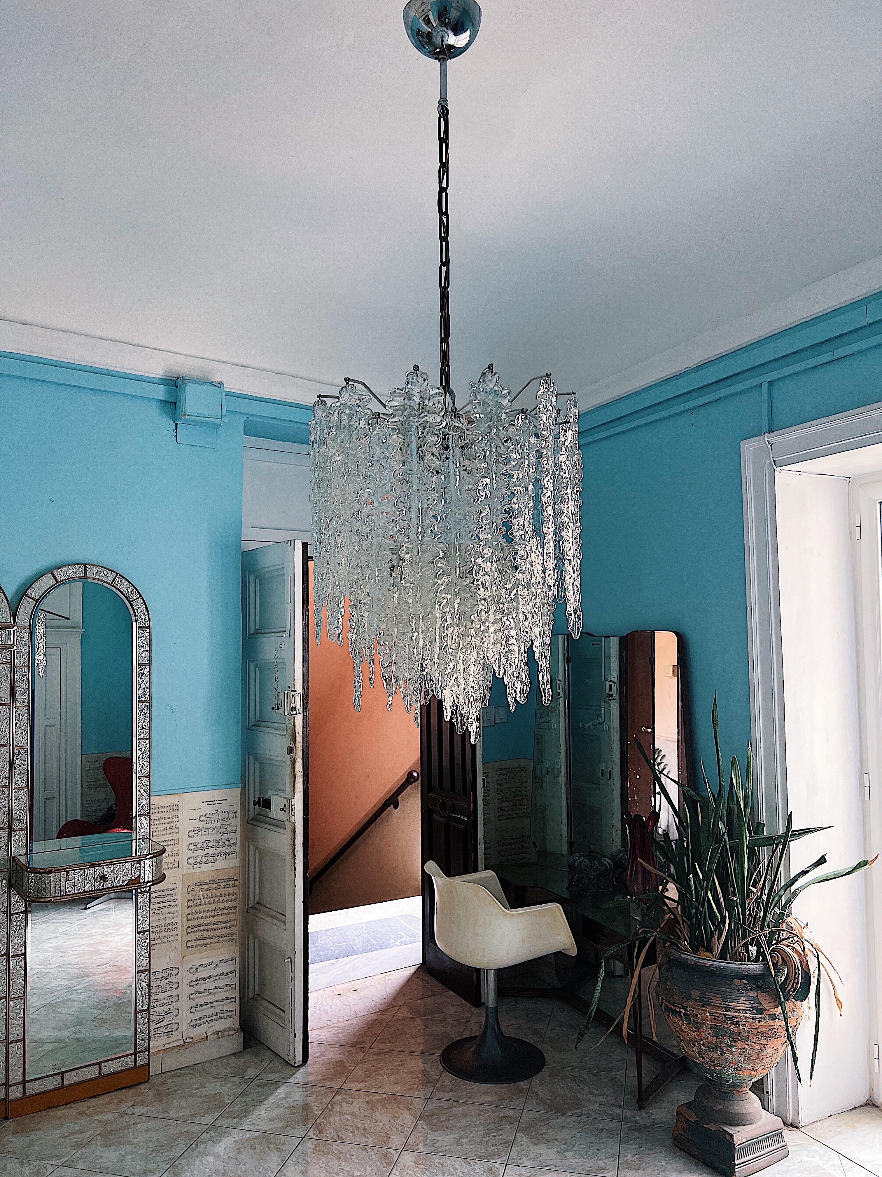 A timeless beauty of Murano glass. This opulent chandelier, a masterpiece, was artfully crafted by Venini in 1960. Its grandeur is composed of 60 meticulously handcrafted Murano glass leaves, gracefully arranged upon a brass base of three tiles.