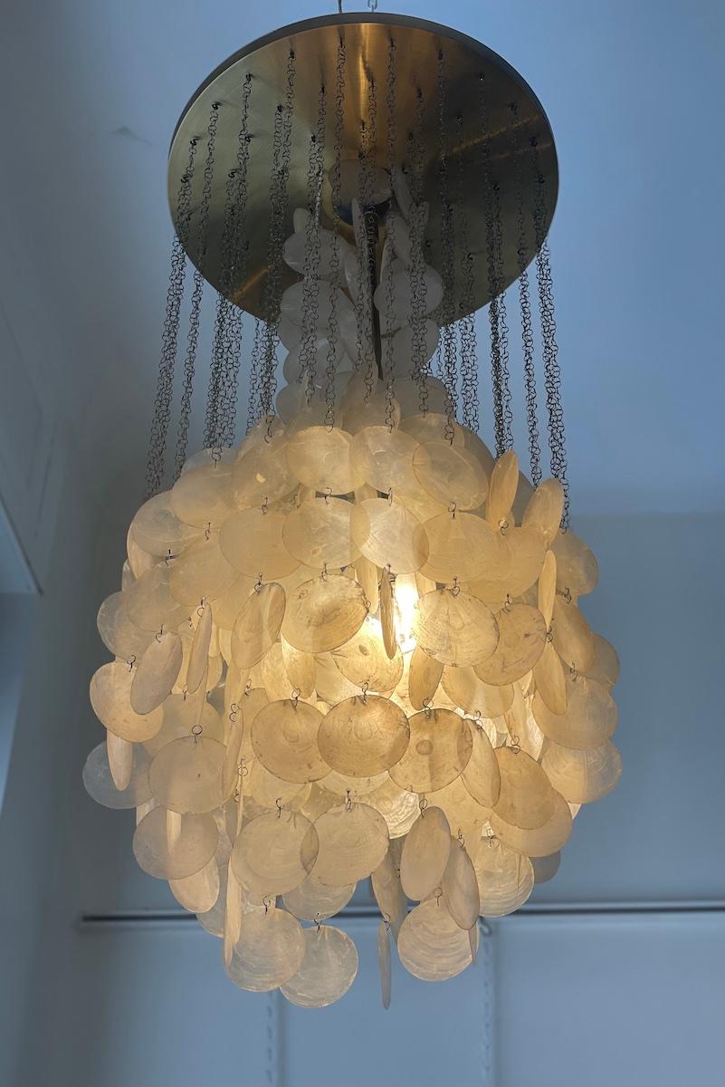 Lustre suspendu conçu par Verner Panton en 1964.
Le lustre se compose d'une structure circulaire en métal doré d'où pendent de nombreuses chaînes métalliques fines. Des disques de nacre, disposés en plusieurs couches, sont attachés aux chaînes. La