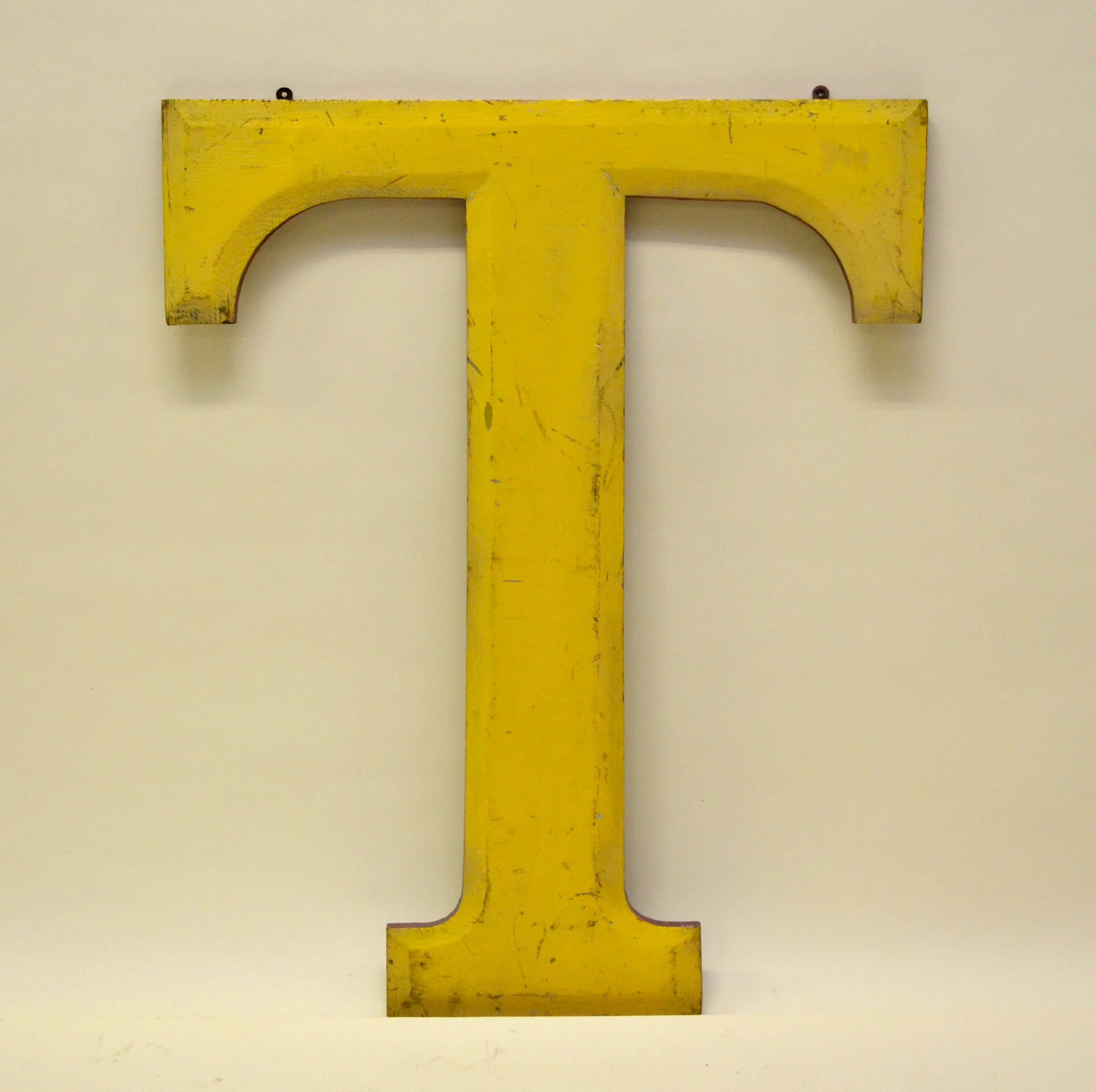 Very large yellow wooden capital letter T with red border made in England probably in the 1960s as part of the sign of a pub.

From the same sign also available in stock letters: R.