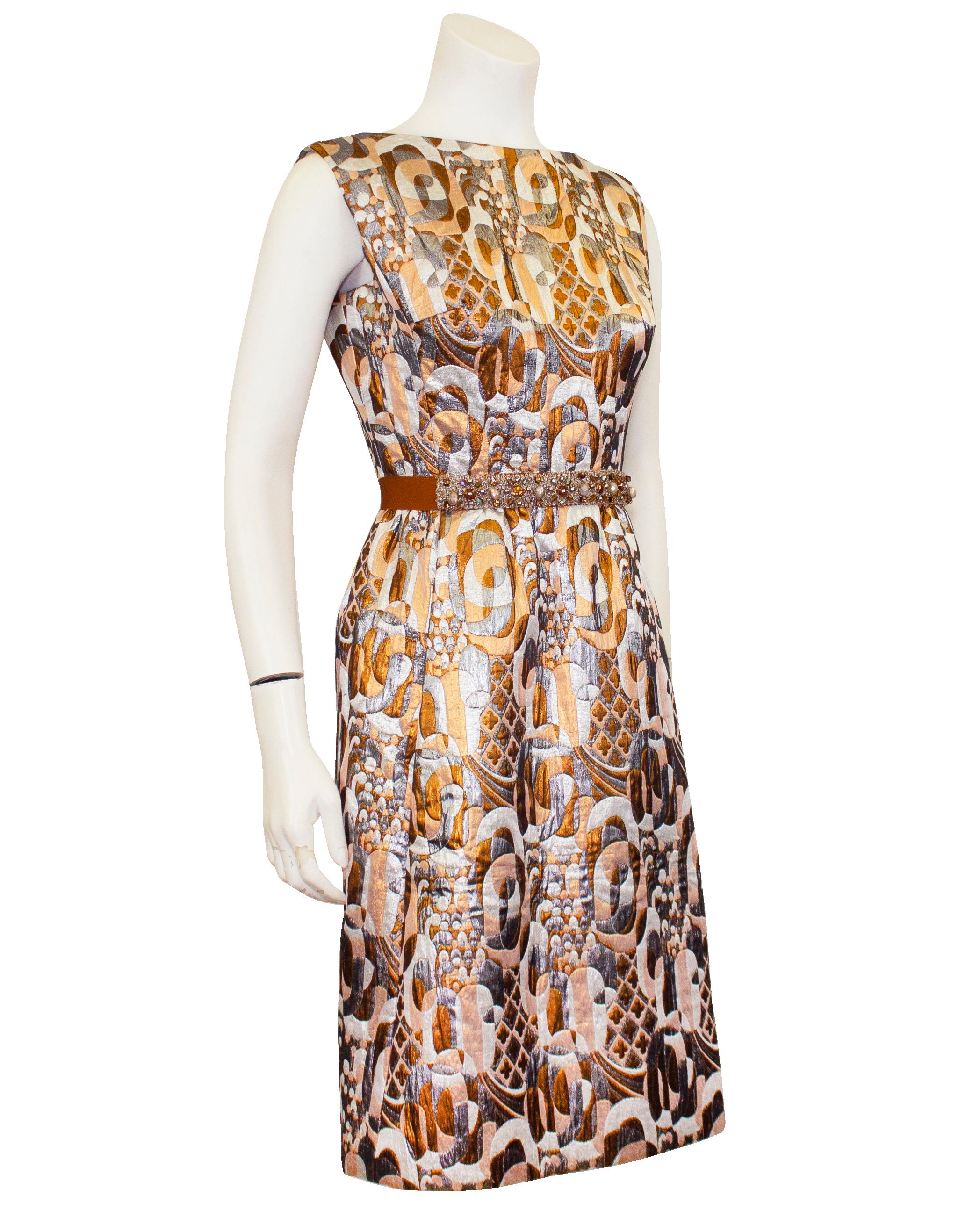 Glitzy and very pretty 1960s Romantica by Victor Costa cocktail dress. Made from a stunning mod, geometric brocade in silver, bronze and metallic white and peach. Sleeveless with a boatneck line. Fitted through the body and the waist is accented
