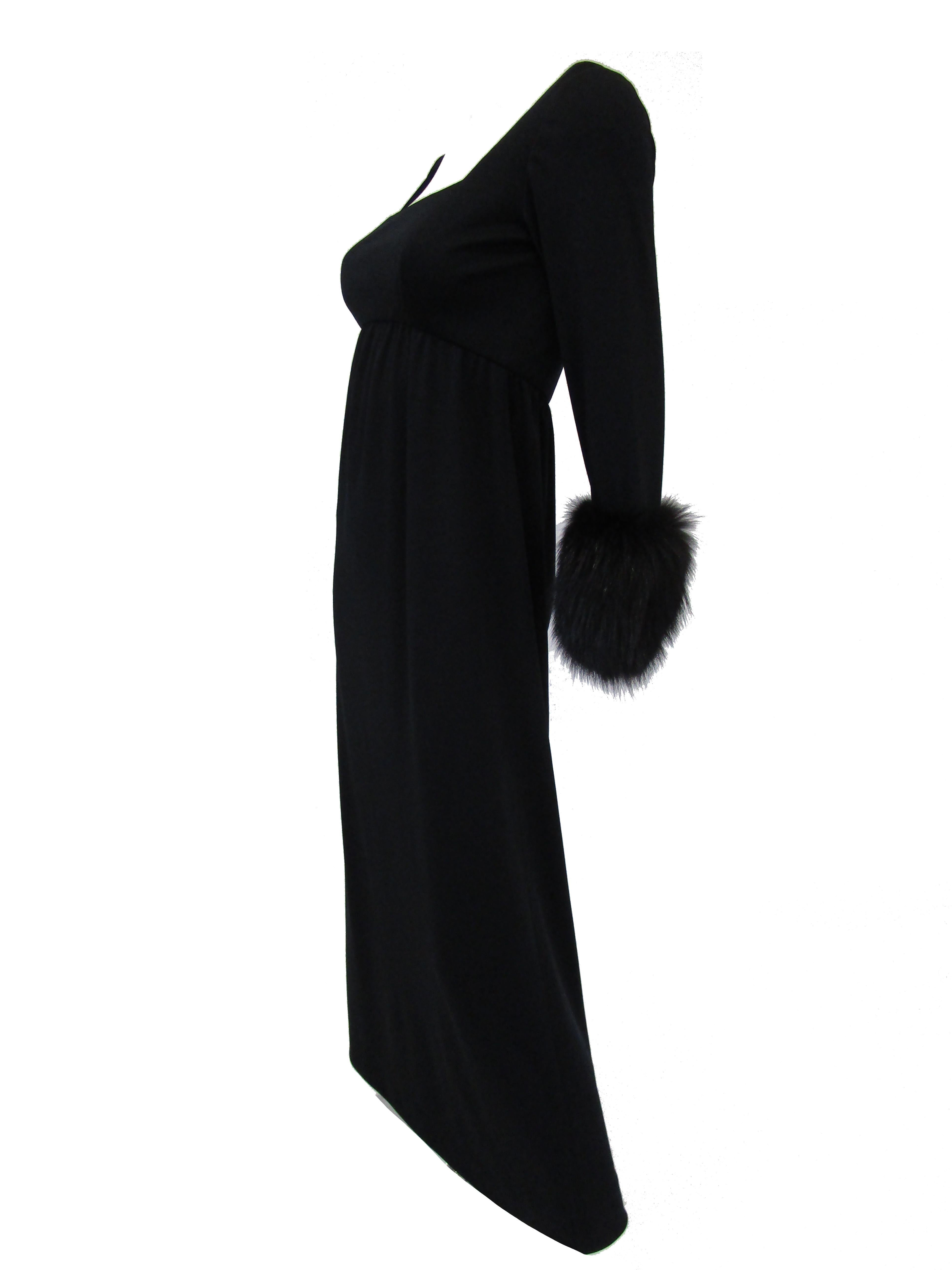 Elegant yet subdued black knit ensemble by Victoria Royal. The maxi dress has fitted bodice with square neckline and empire waist that gives way to an A - line skirt. Long sleeves feature glossy black fox fur cuffs. The vest is maxi length as well,