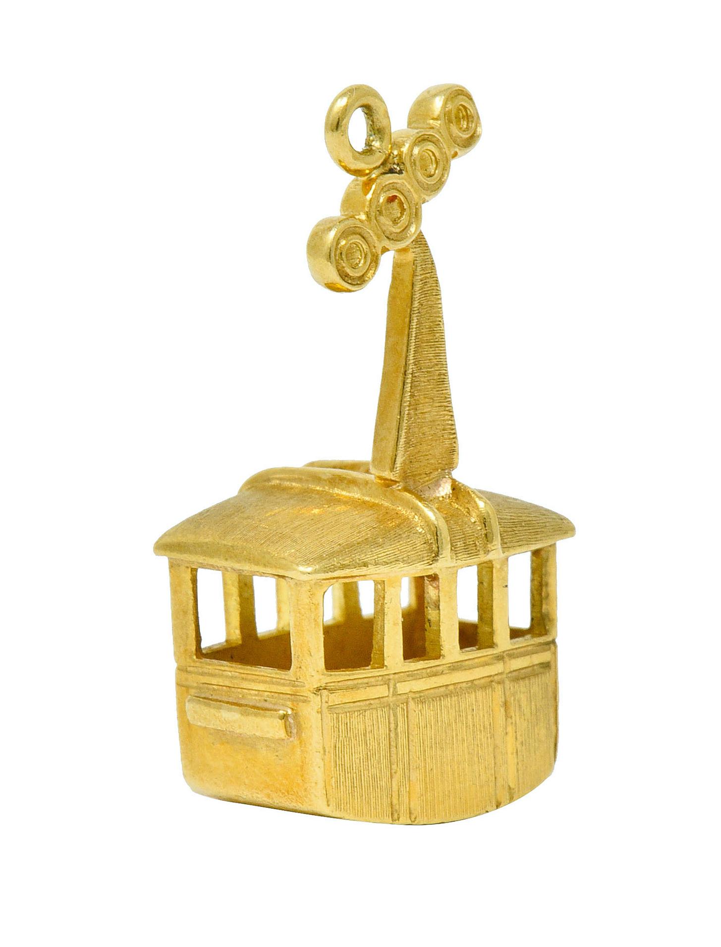 Aerial cable car charm is a dimensional rectangular form

With pierced out windows, a strong brushed finish, and topped by pulley wheels

Tested as 18 karat gold

Circa: 1960s

Measures: 1/2 x 1 1/8 inches

Total weight: 5.5 grams

Snowy. Alpine.