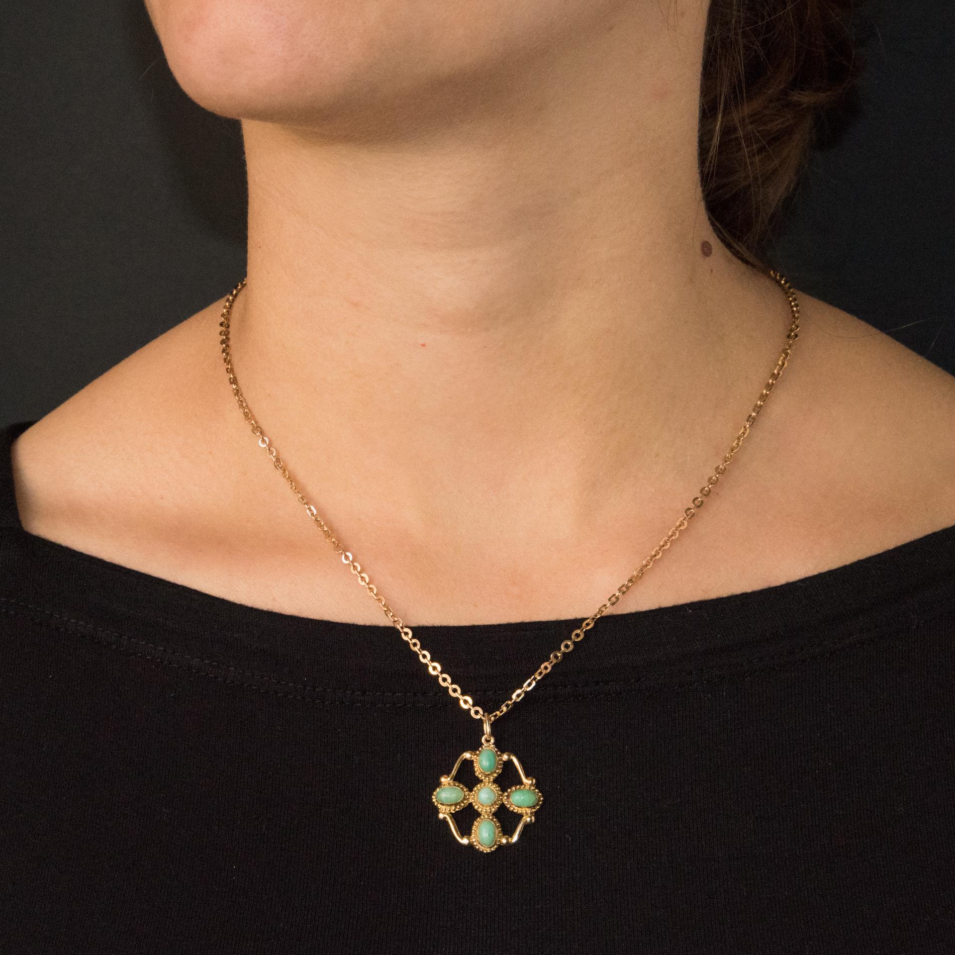 Pendant and its chain in 18 karats yellow gold, weevil hallmark.
This pendant is made of a cross motif set with a carved cross on each branch of cabochon amazonites. Golden ties hold each branch of the cross. The chain is a flat jaseron mesh with