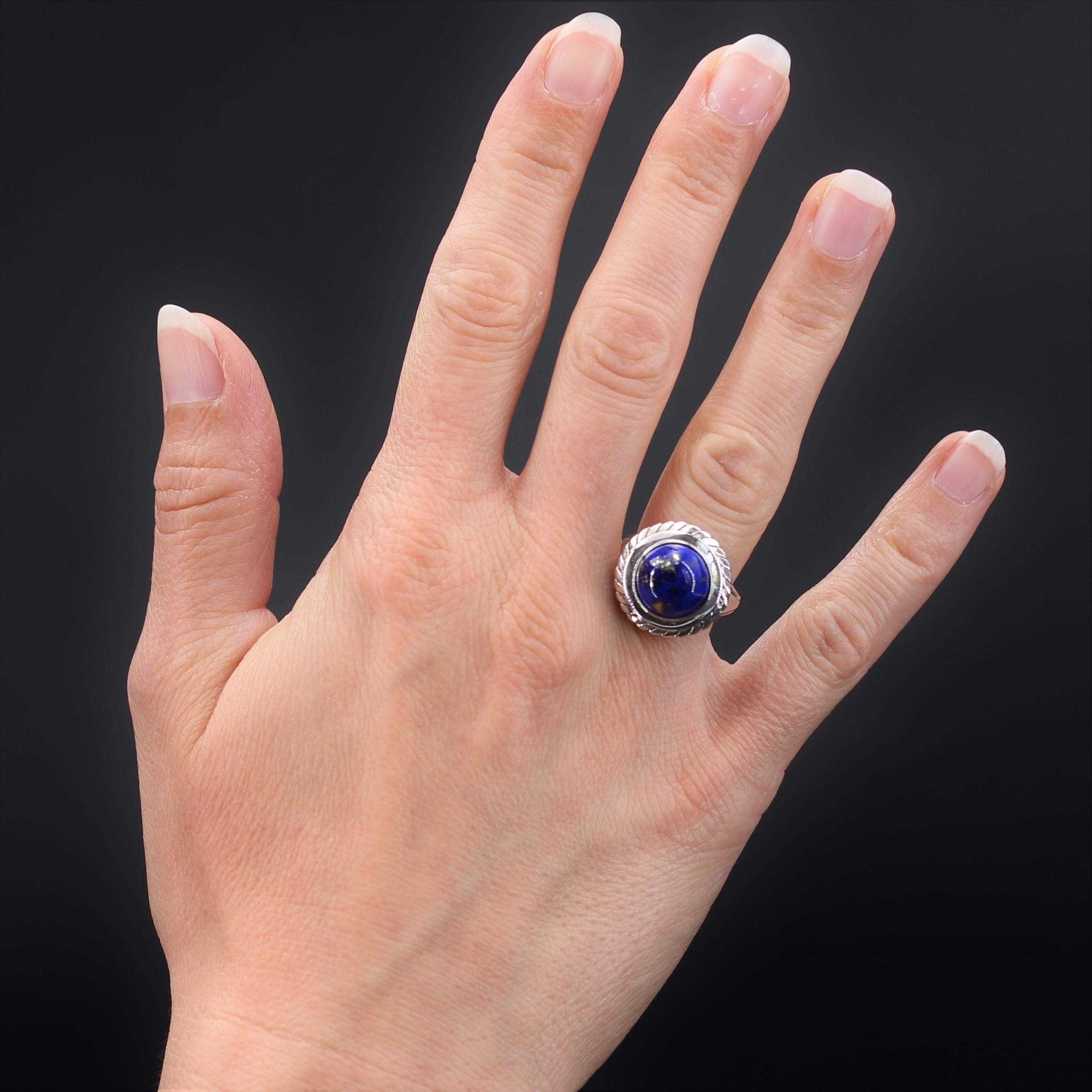 Ring in 18 karats white gold.
Round in shape, it is set with a lapis lazuli cabochon in a closed setting surrounded by a shiny smooth gold circle and a chiseled second circle. The basket is perforated and the departure of the double ring is set with
