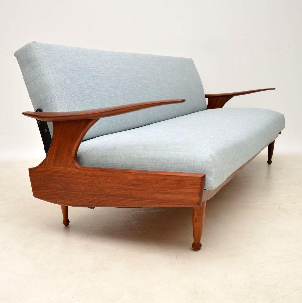 An amazing vintage sofa bed by the high end manufacturer Greaves and Thomas, this is beautifully made from solid afromosia wood. The design is really stunning and quite unusual, with lovely sweeping arms that appear to float. The condition is