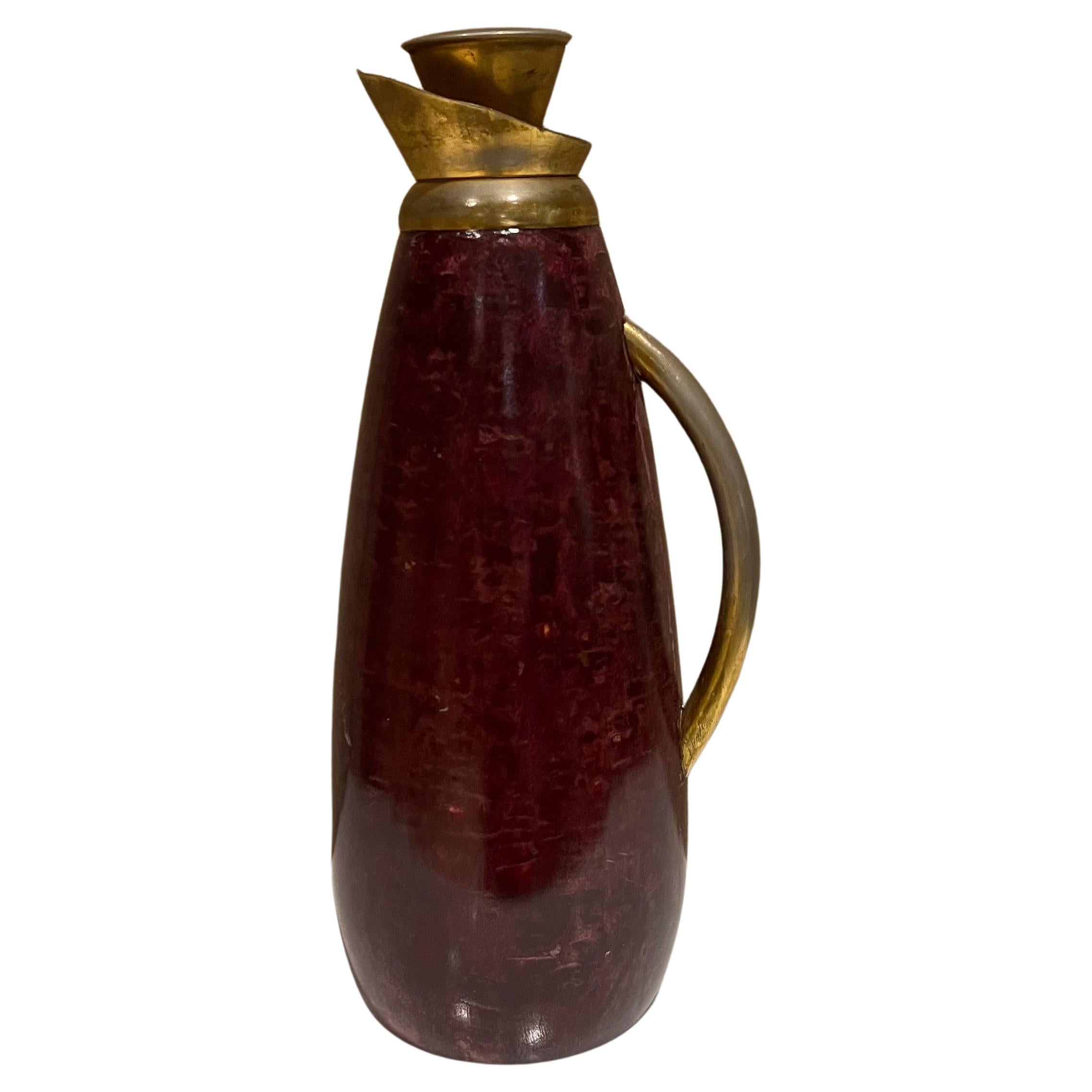Pitcher Aldo Tura
Italy 1960s Aldo Tura vintage pitcher carafe in purple wine parchment goatskin
Handle and cork stopper in brass plated metal. 
Label from the maker. 
Measures: 14.25 tall x 6.5 wide x 4.75 diameter
Please expect preowned