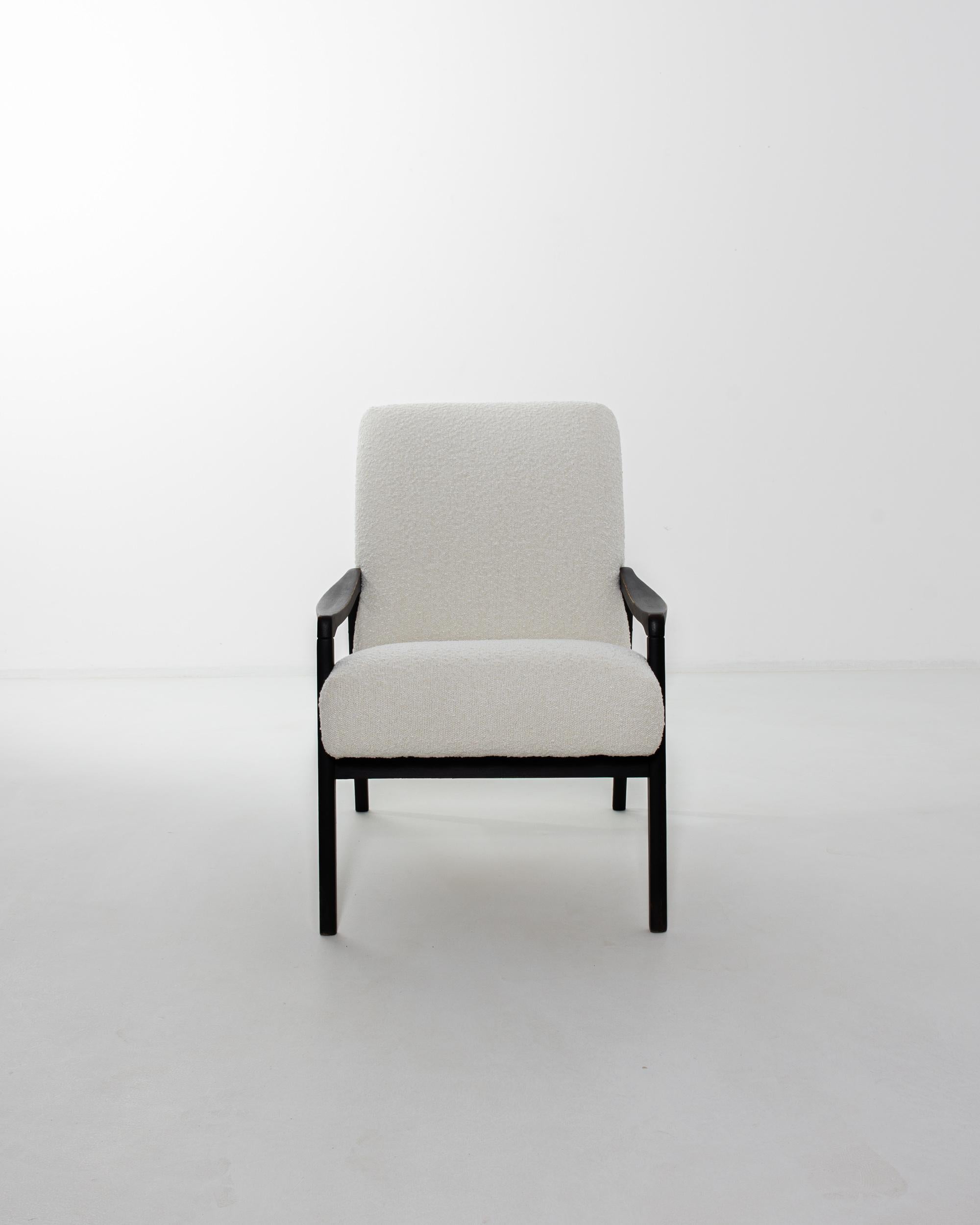 A wooden armchair produced in the former Czechoslovakia, with the design attributed to Jiri Jiroutek. This 1960s design is re-upholstered in updated ivory boucle upholstery; the airy tone was chosen to compliment the rich black of the hardwood