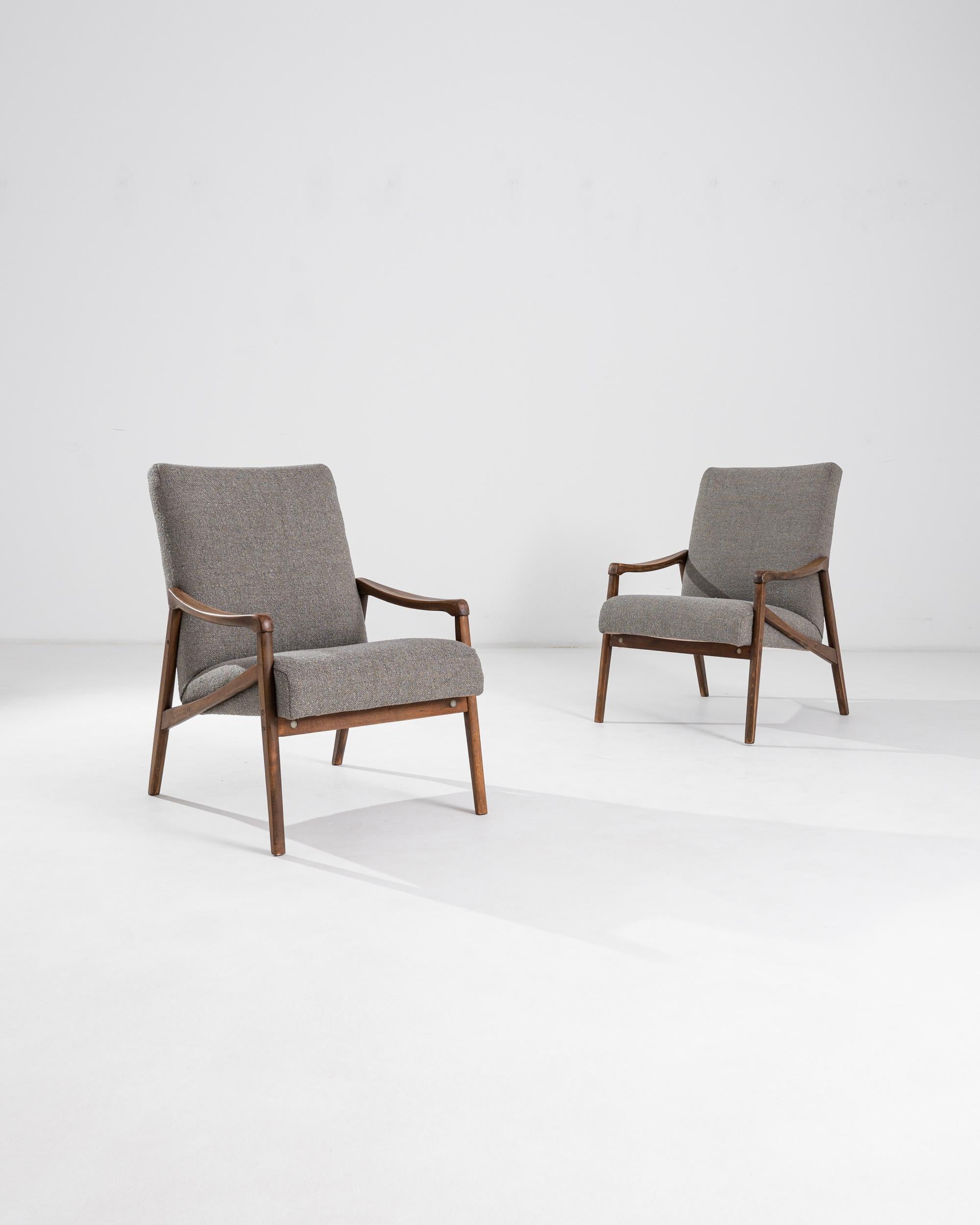 A pair of armchairs produced in the former Czechoslovakia, with the design attributed to Jiri Jiroutek. This 1960s design is re-upholstered in an updated taupe boucle upholstery; the neutral tone was chosen to compliment the polished patina of the