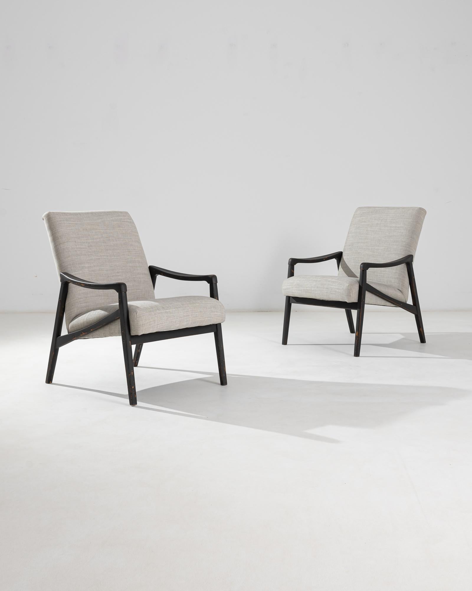 Paire de fauteuils produits dans l'ancienne Tchécoslovaquie, dont le design est attribué à Jiri Jiroutek. Ce modèle des années 1960 a été retapissé dans un revêtement gris bruyère actualisé ; le ton neutre a été choisi pour compléter la patine polie