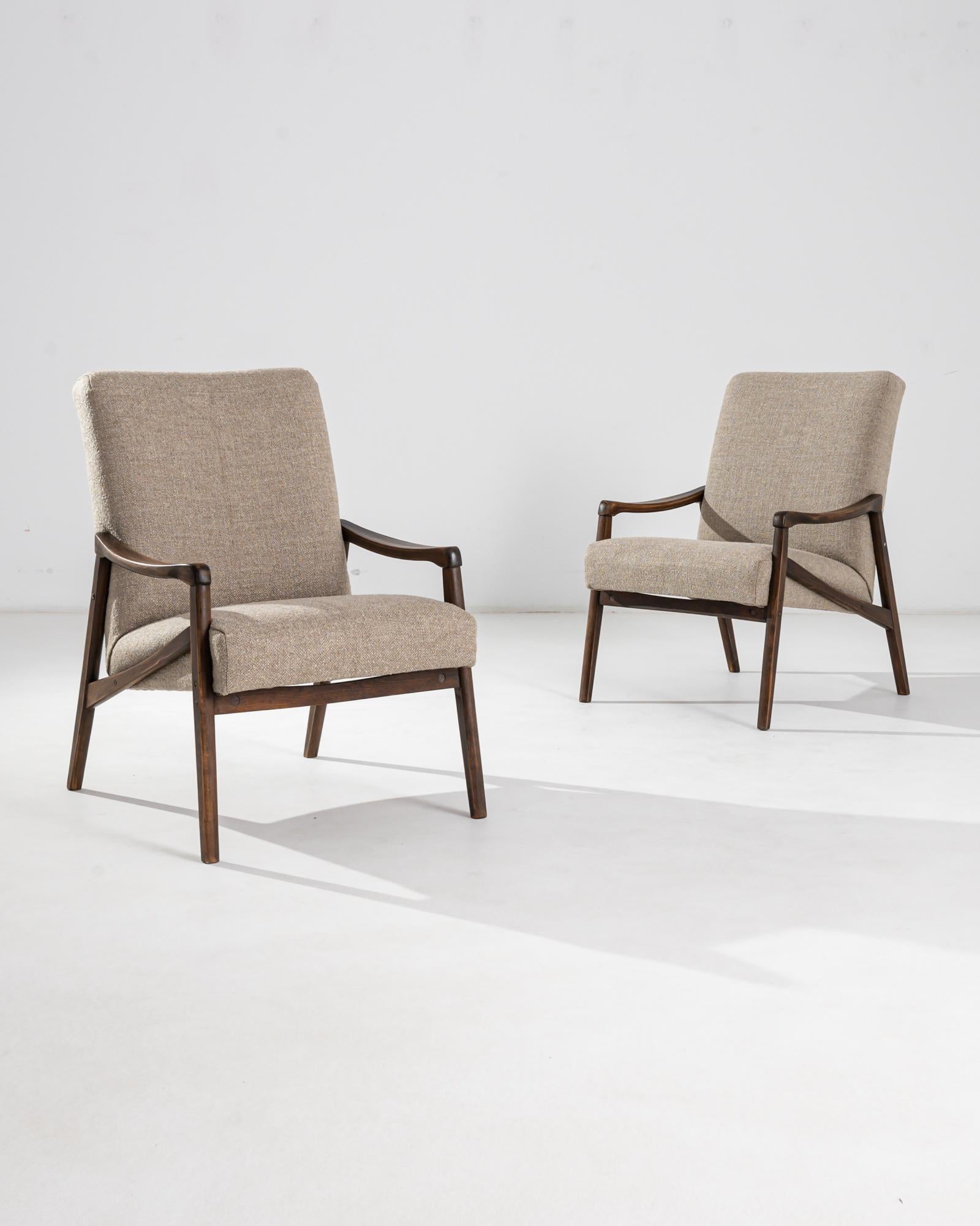 Une paire de fauteuils produits dans l'ancienne Tchécoslovaquie, dont le design est attribué à Jiri Jiroutek. Ce design des années 1960 a été retapissé en beige, un ton neutre qui s'harmonise avec la patine polie du cadre en bois dur. Angles