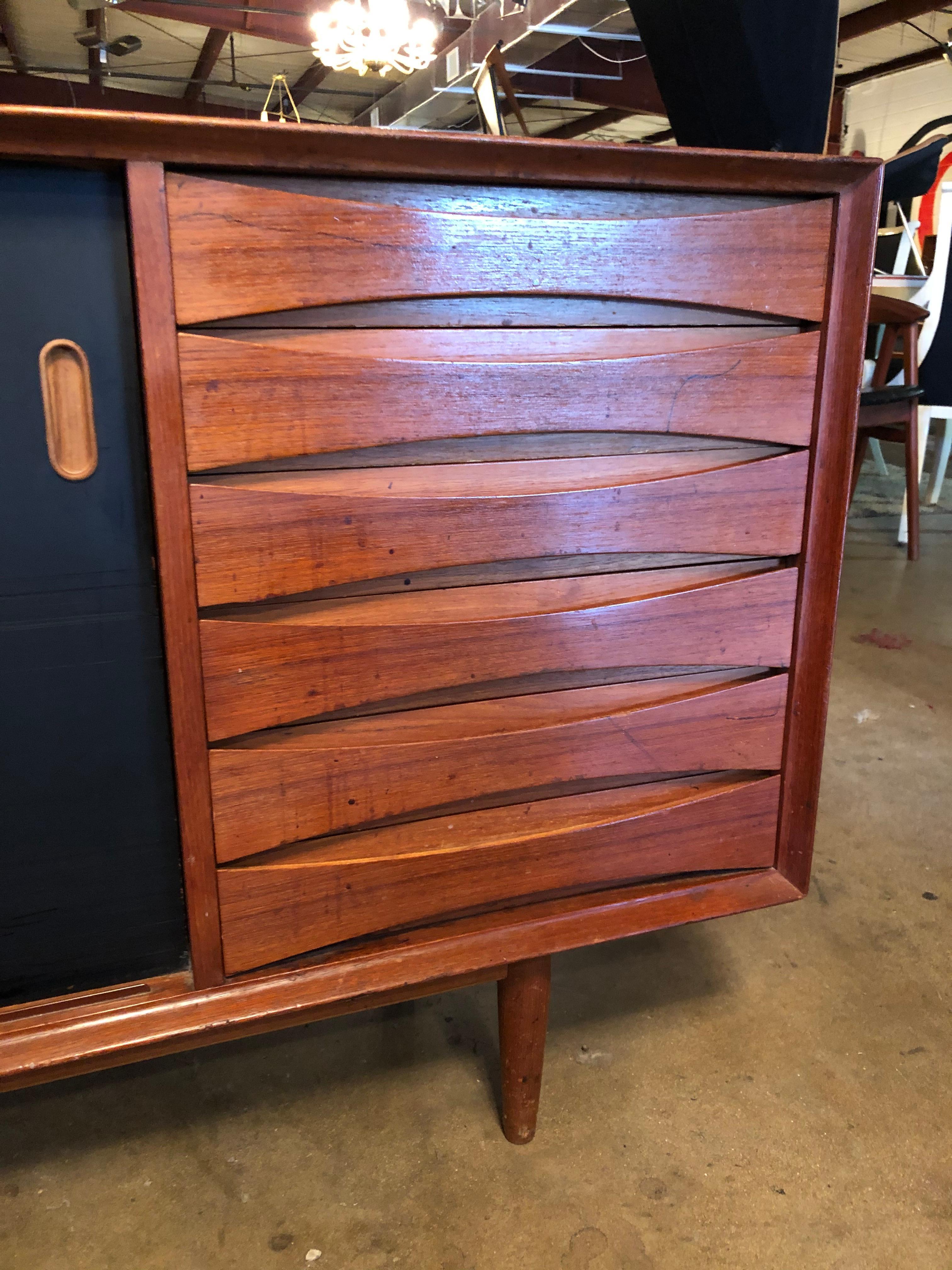 Designed by Arne Vodder for Sibast, this vintage teak credenza is in overall good condition. Features six drawers with concave edge pulls and dove-tailed joints, adjustable shelving in cabinets with reversible black lacquer and teak sliding