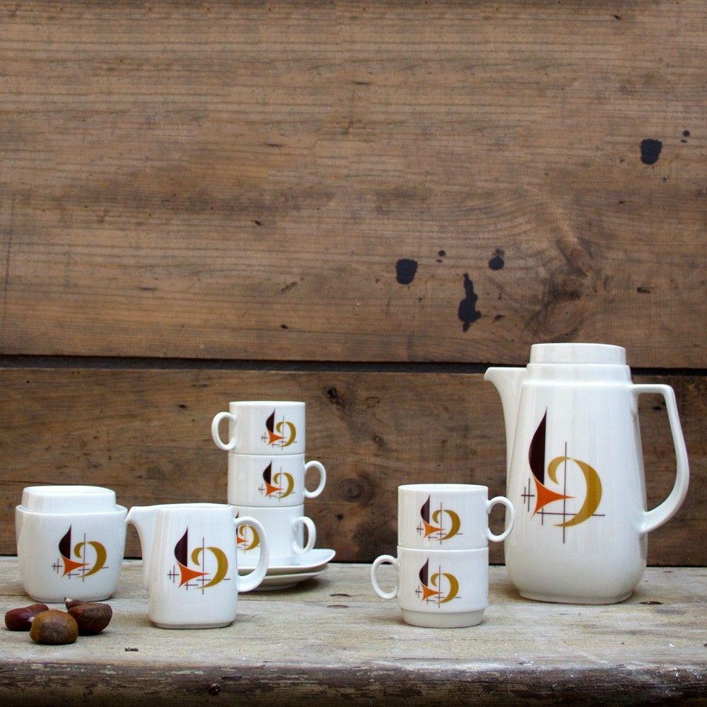This 1950s Bavarian coffee set is made of white porcelain and detailed with a unique design of lines and curved shapes on the front of each piece. The design is in dark blue, orange and dark yellow brown colors. 

The set consists of:
- Coffee