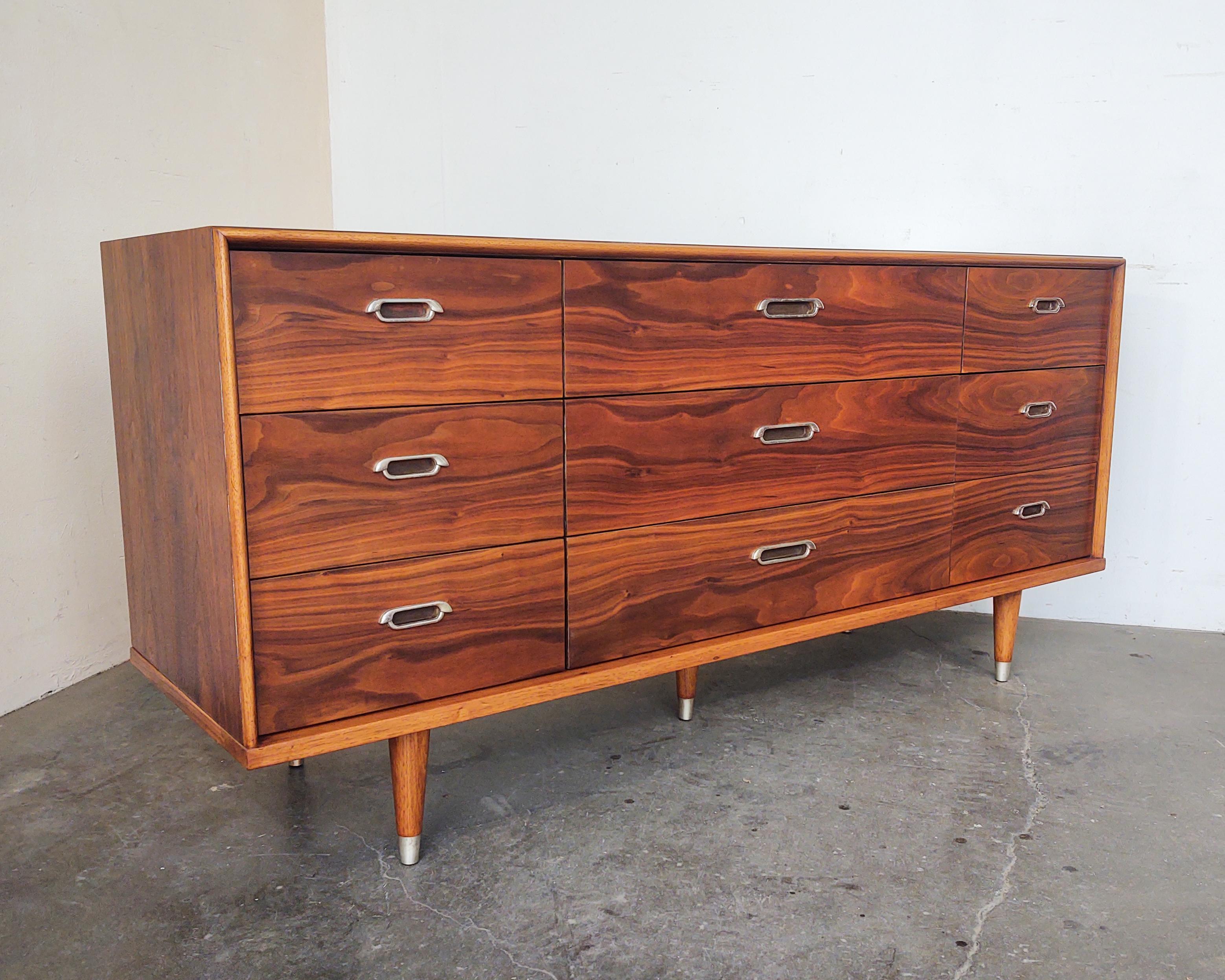 Walnut lowboy dresser by B.P. John circa 1962. Completely refinished to show stunning walnut wood grain. Nine drawers featuring cast aluminum pulls and dovetail joinery. Tapered legs with matching aluminum caps.

Measures: 64
