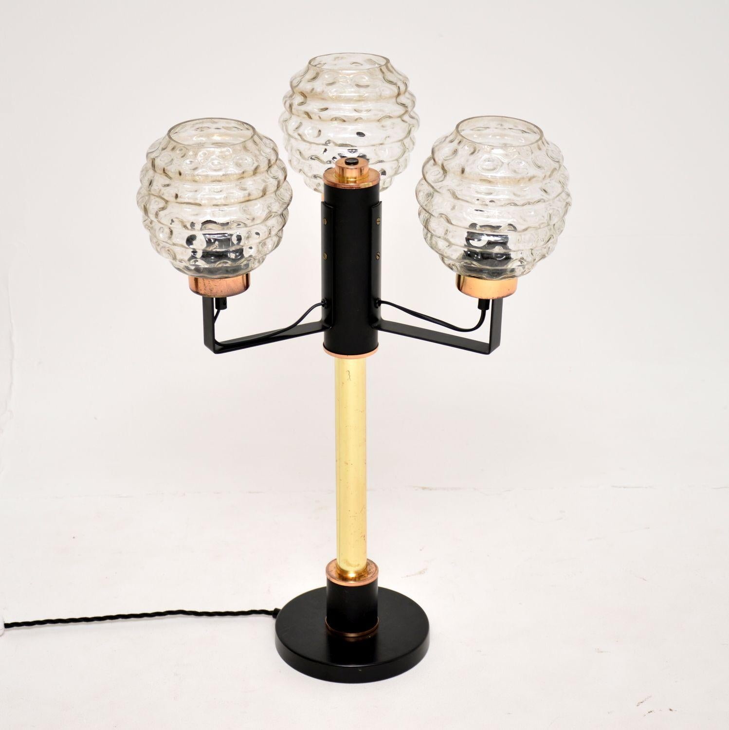A large and impressive vintage table lamp, beautifully made from brass, steel and glass. This was made in England, it dates from the 1960’s.

The design is fantastic, the solid brass column sits on an ebonised steel base, with three ebonised steel