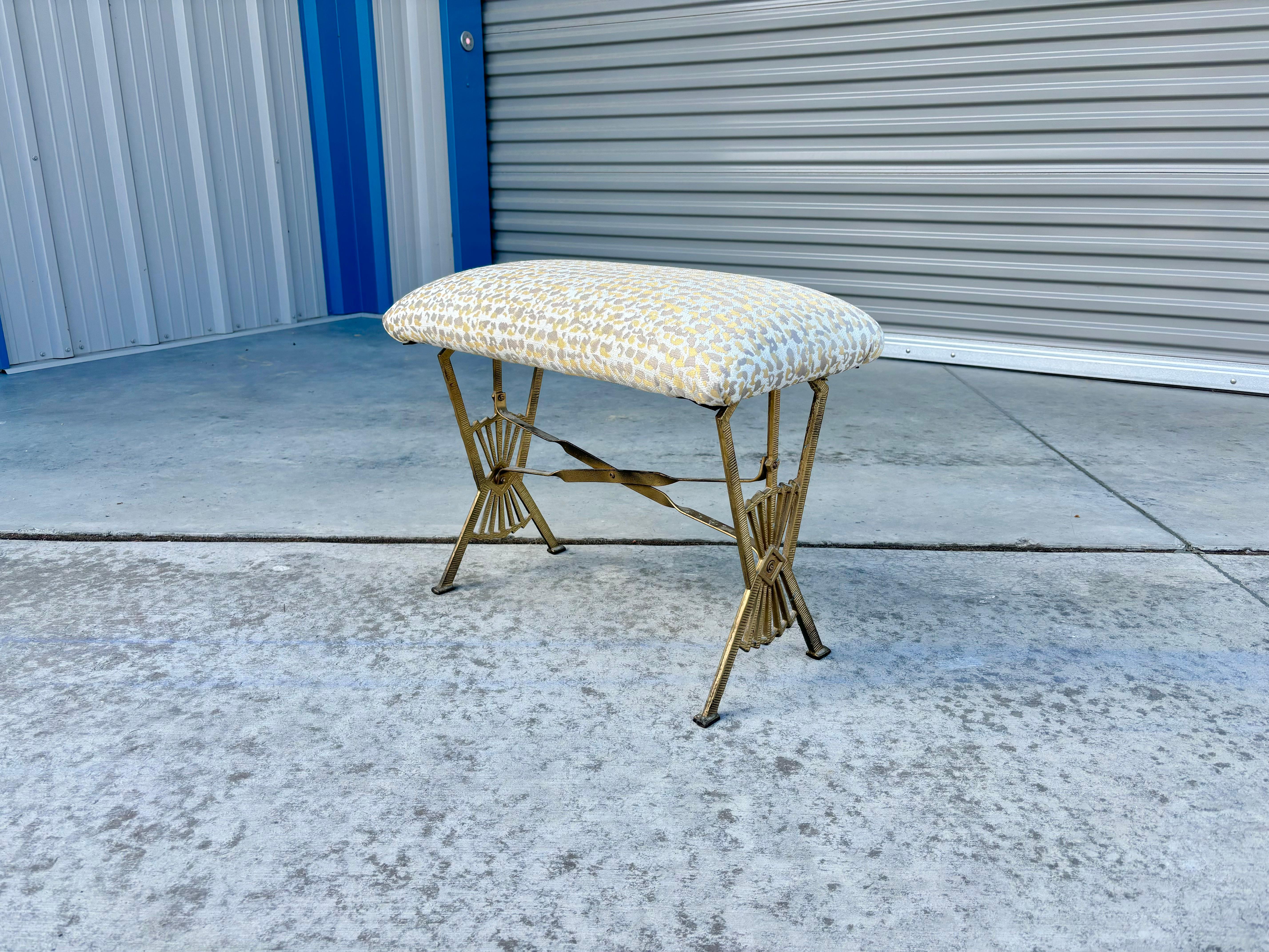 Vintage brass ottoman designed and manufactured in the United States circa 1960s. This stunning ottoman boasts a unique and intricate brass metal base that will catch any discerning individual's eye. The cushion has been recently reupholstered to