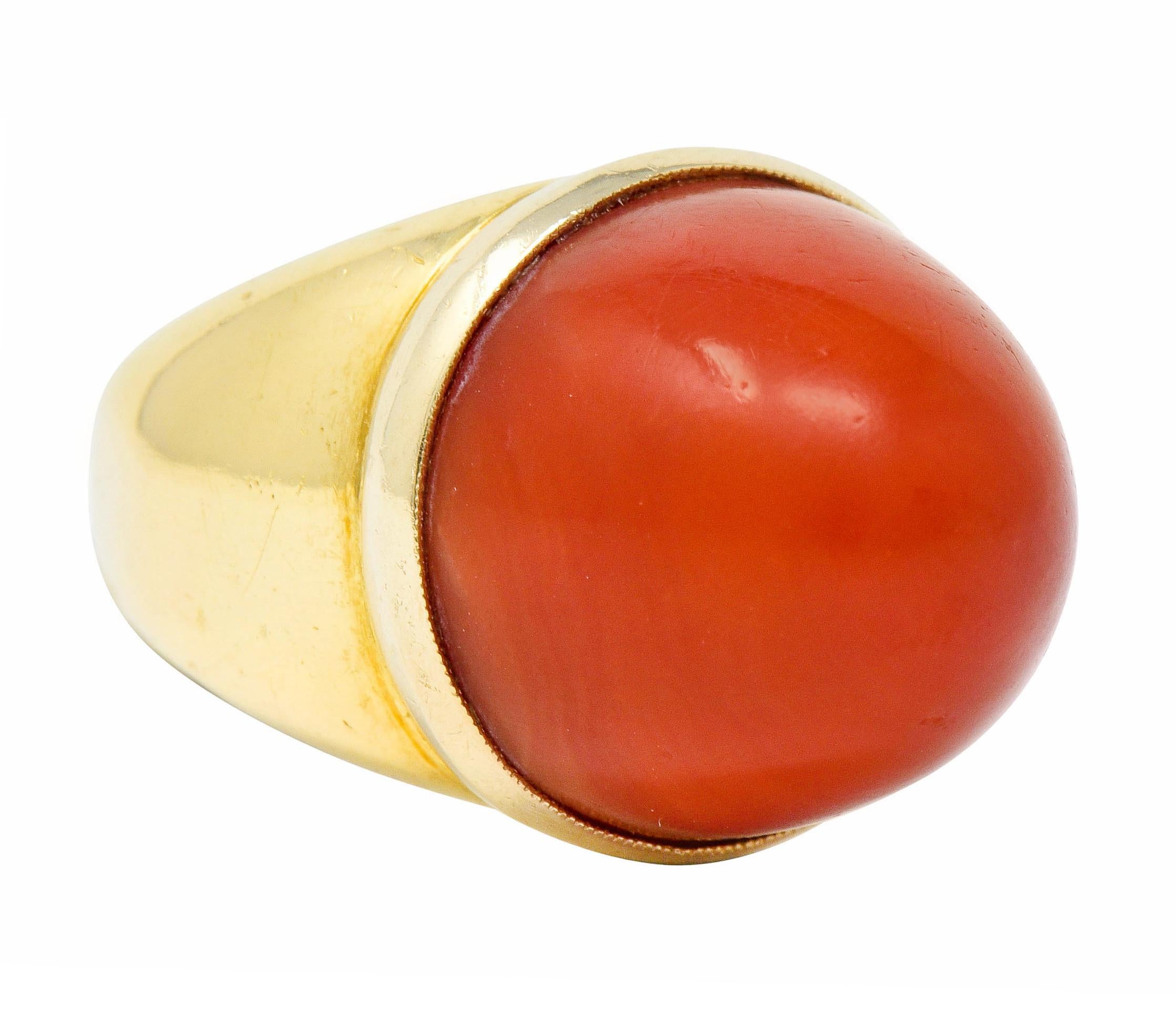 Centering a towering coral bullet cabochon, opaque and a strongly reddish-orange color with moderate swirled color distribution

Bezel set in a polished gold mounting

Tested as 18 karat gold

Circa: 1960s

Ring Size: 5 3/4 & sizable

Measures: 17.8