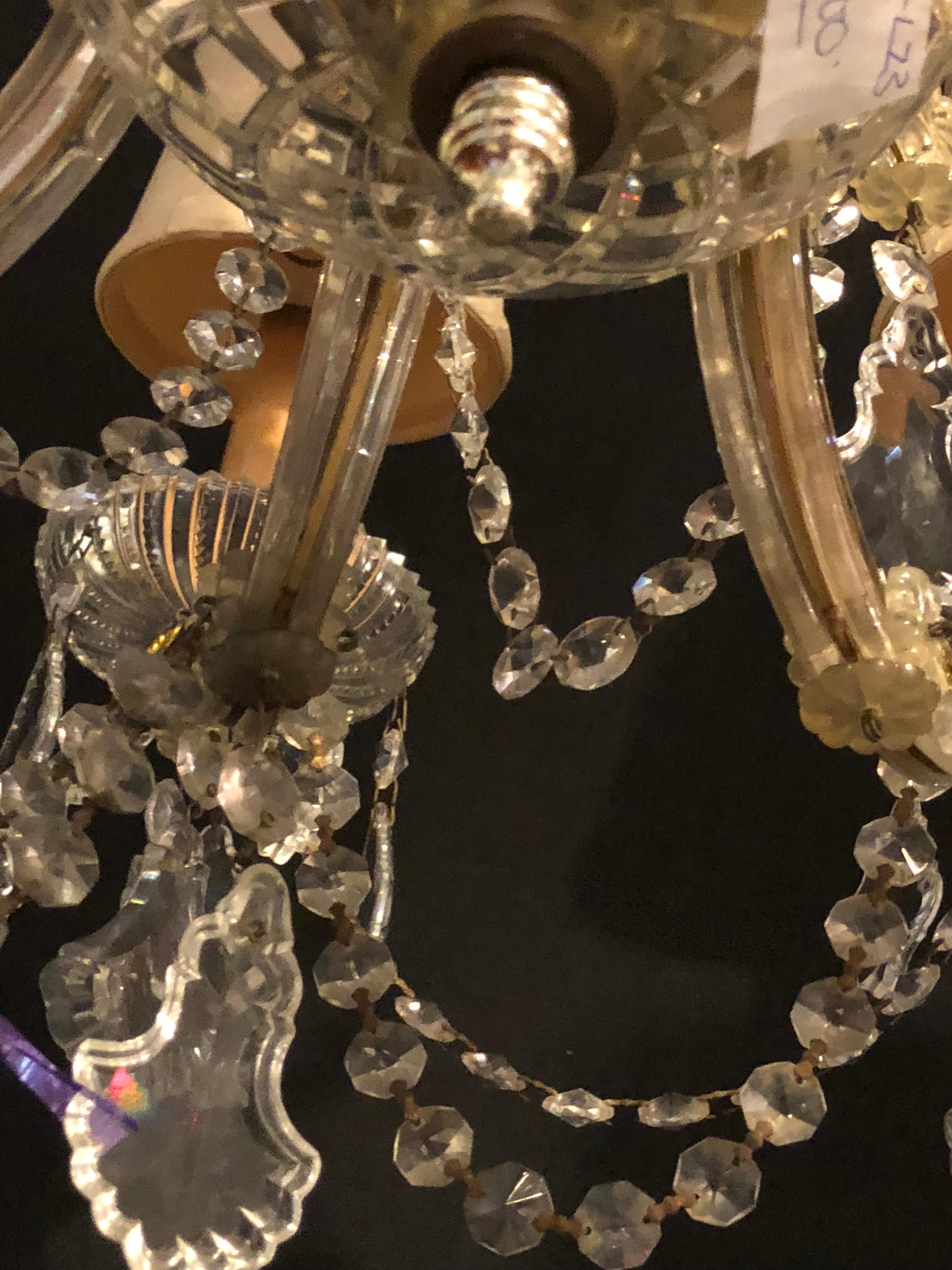 An elegant neoclassical style iron and crystal chandelier with eight off-white shades. The chandelier is professionally polished and rewired.