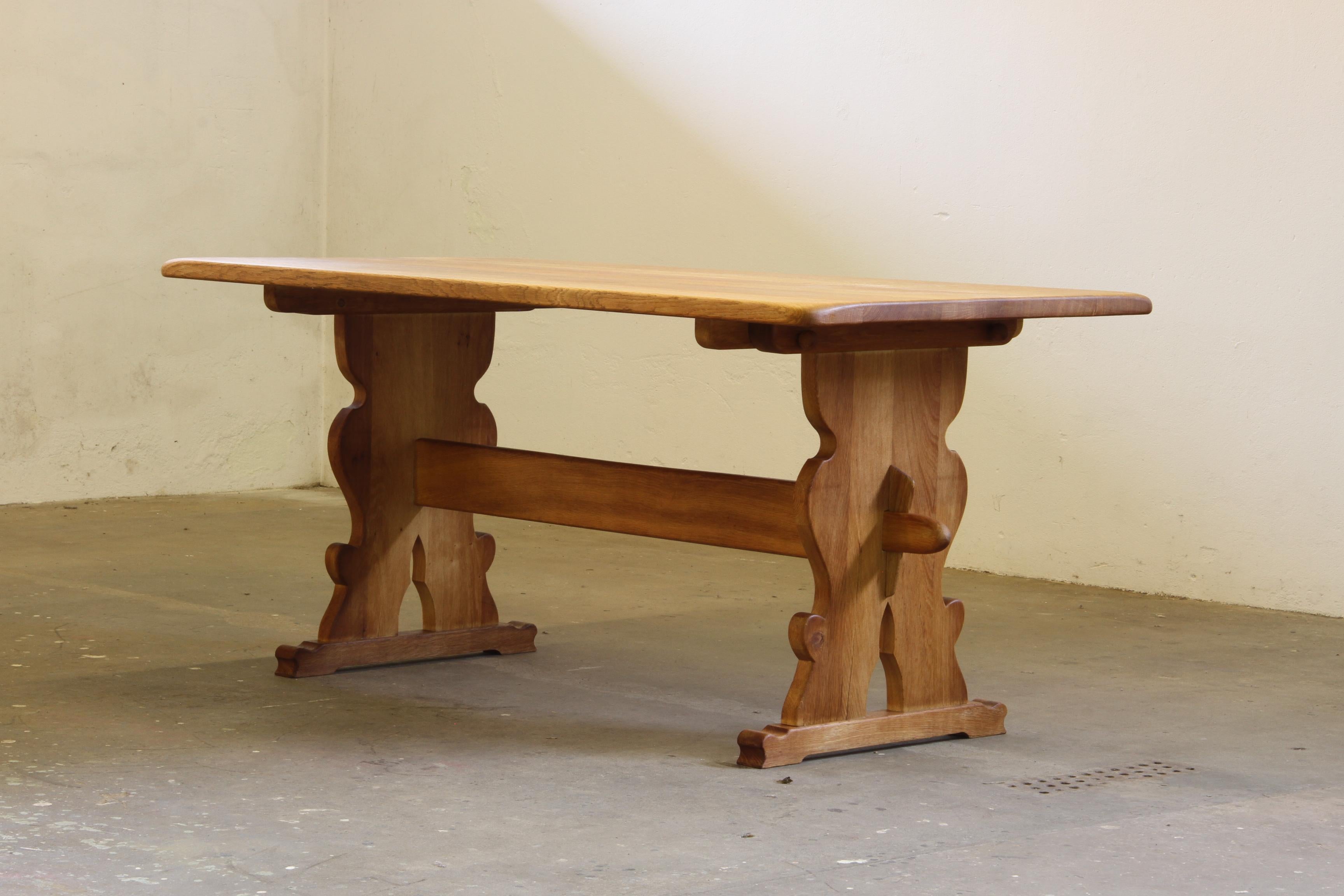 This exquisite vintage Danish farmhouse dining table, crafted in the 1960s/70s, seamlessly blends French countryside charm with refined mid-century craftsmanship. Made from solid oak, it features a trestle base with simple yet elegant carved