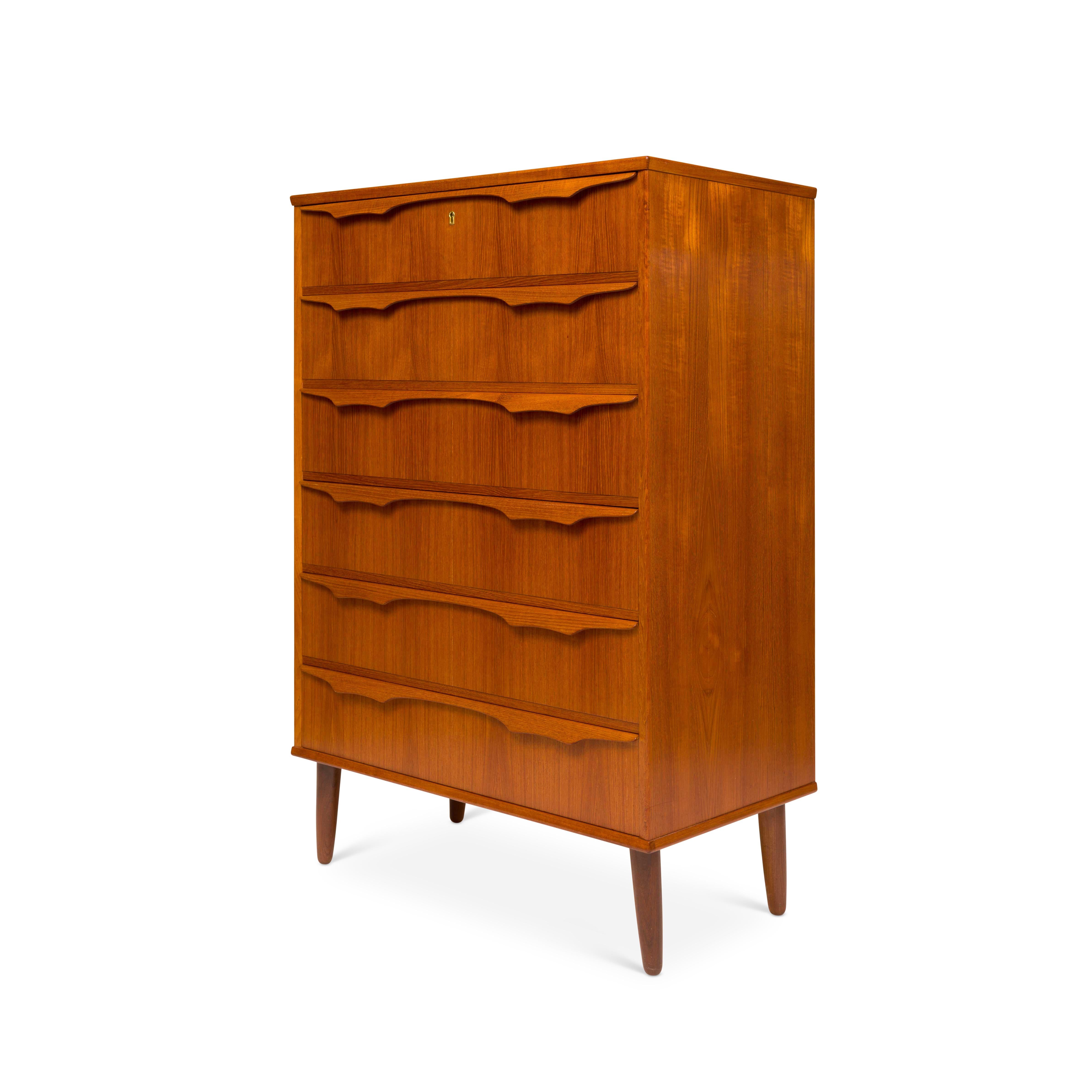 This Danish tallboy chest of drawers embodies the essence of Mid-Century design. Its six drawers, adorned with sculptured wooden handles and seamless dovetail joins, effortlessly combine functionality with elegance. The natural teak grain adorns its