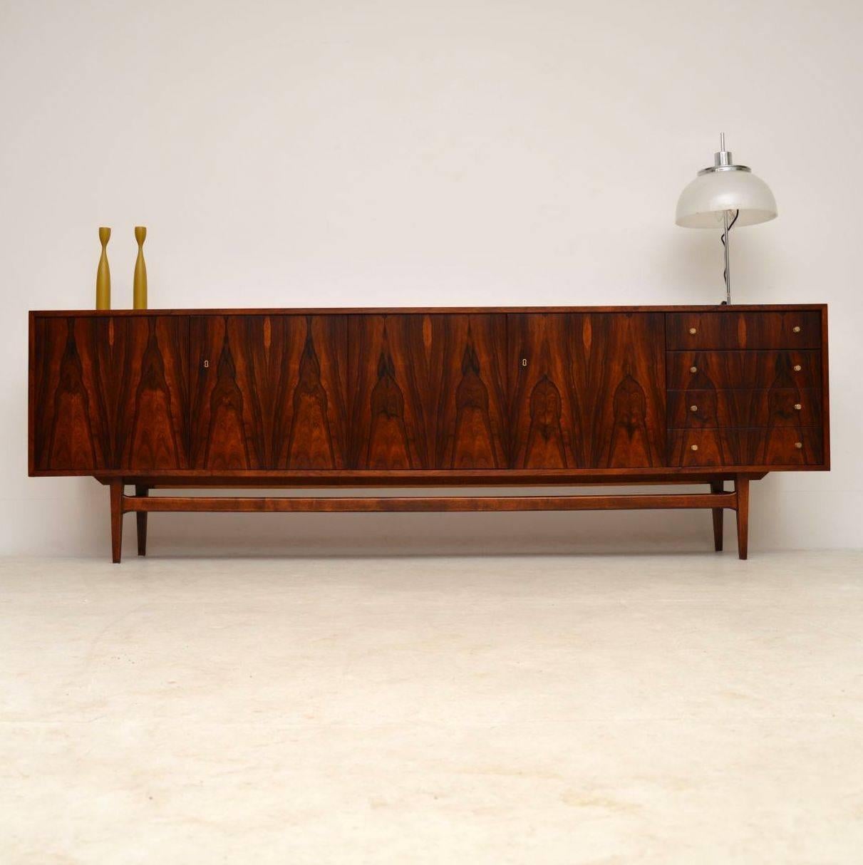 A spectacular vintage sideboard, this was made in Denmark and it dates from the 1960s-1970s. It is beautifully styled on splayed legs, with lovely brass handles. The grain patterns are phenomenal throughout and the color is gorgeous as well. We have