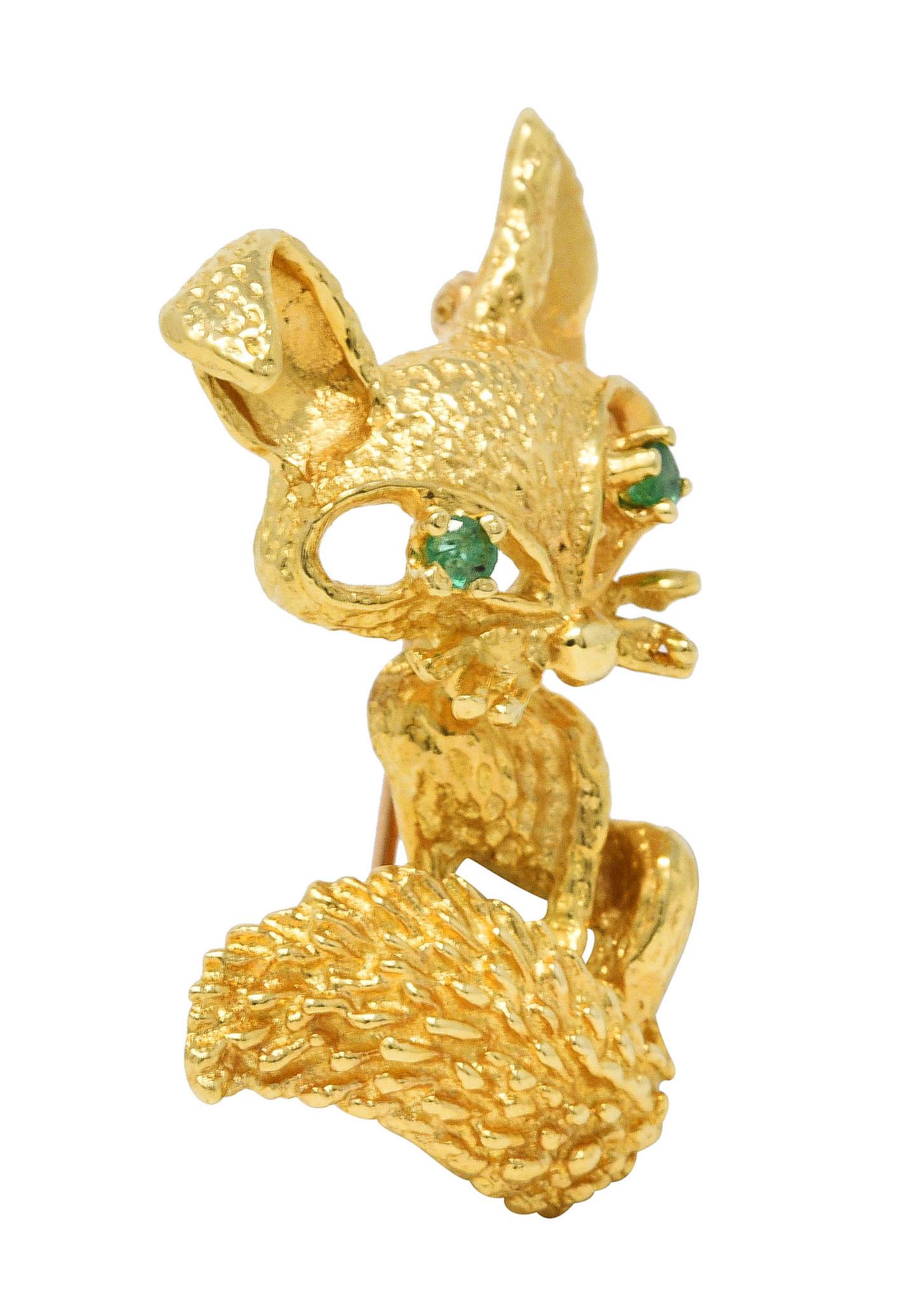 Brooch is designed as a stylized fox with bold features and a bushy tail

Accented by prong set round cut emerald eyes - transparent bright green

With textured fur throughout

Completed by hinged pinstem with locking closure

Stamped 18k for 18
