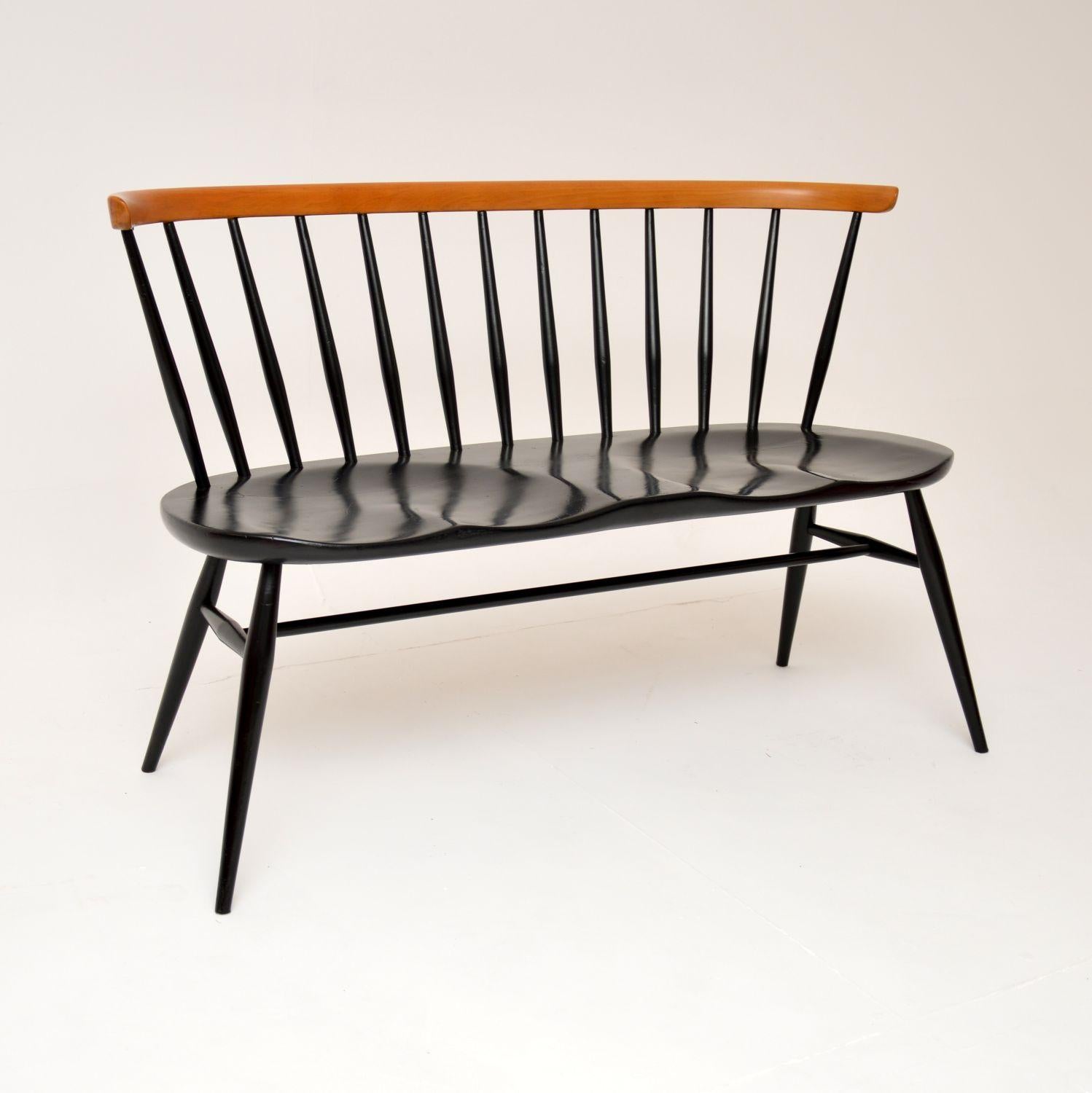 A stunning and iconic design, this original two seat bench is an early model by Ercol. It was made in England, and dates from the 1960’s.

It is of amazing quality, with an elegant yet sturdy design. The frame is solid elm and is mostly ebonised,