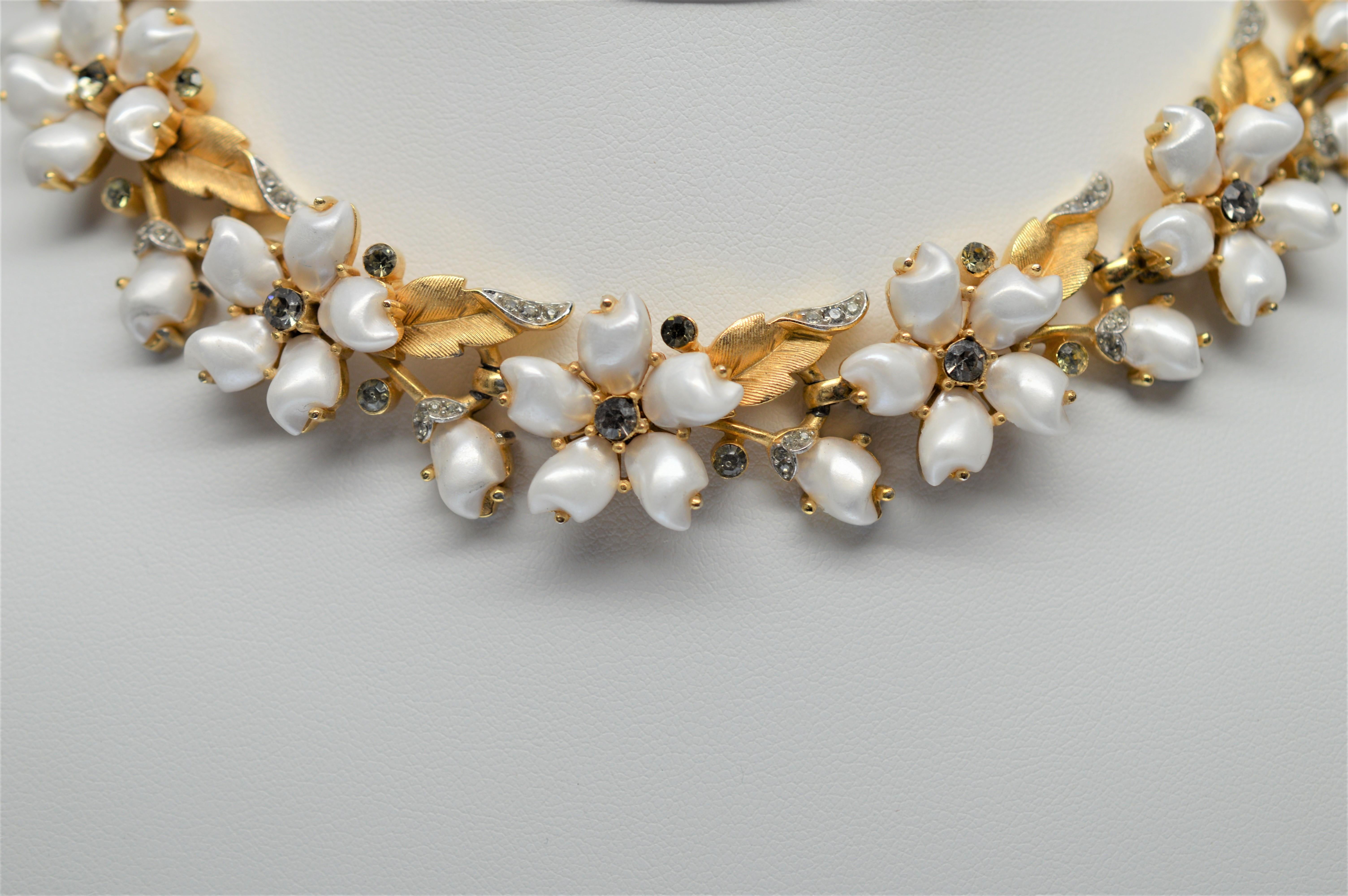 Fabulous Faux Pearl Choker Necklace with Rhinestone Accents, fourteen inches in length with twelve floral blooms created from faux pearl beads as petals accented with rhinestone centers. Faux gold leaves tipped with rhinestones are intertwine in a