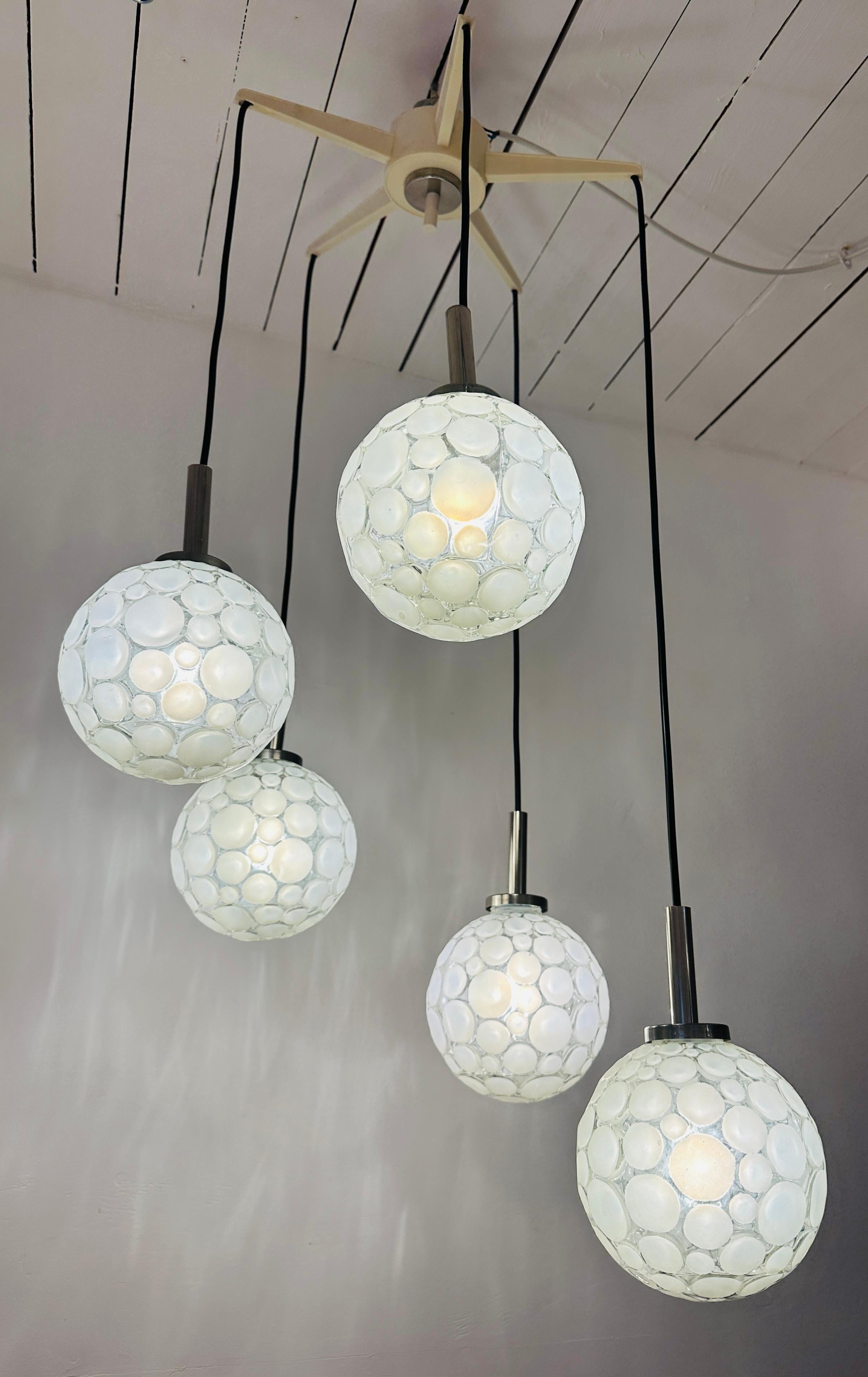 Plafoniera a cinque globi a cascata, vintage, degli anni '60, prodotta da Graewe in Germania.  I globi sono sospesi al soffitto da una stella di plastica rigida a cinque punte che nasconde il cablaggio e li separa.  I globi si agganciano al