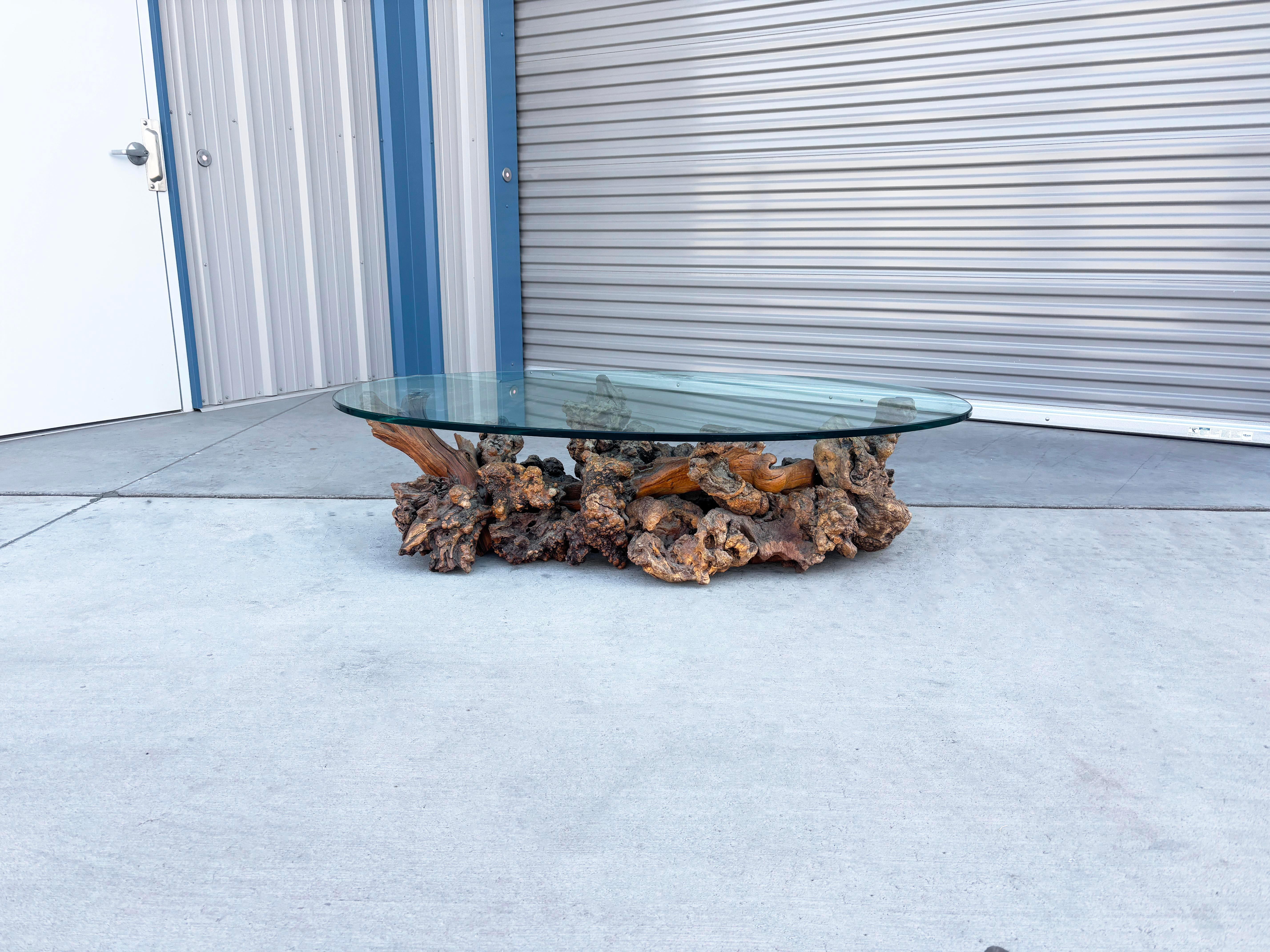 This stunning vintage Burlwood coffee table features a 0.5 mm thick oval glass top that elegantly rests on a beautifully crafted Burlwood base. The base showcases the exquisite grain patterns of the burlwood, adding a rich texture and warmth that