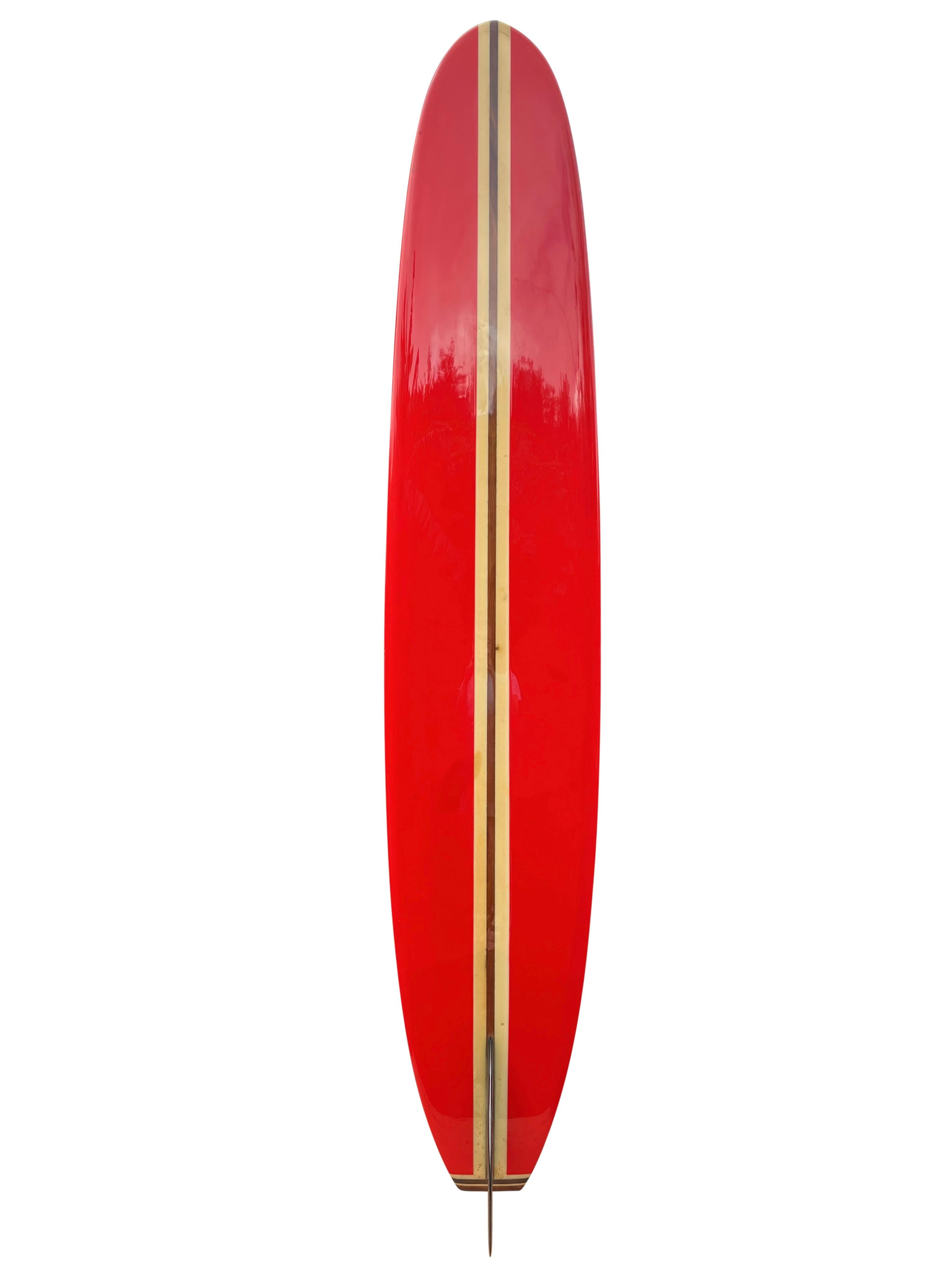 Mid-1960s Greg Noll custom longboard. Features gorgeous bright red panels, redwood stringer, and three piece wooden tail block. Beautiful jet-black single fin with signature wide square tail. A stunning example of a mid-1960s longboard made under
