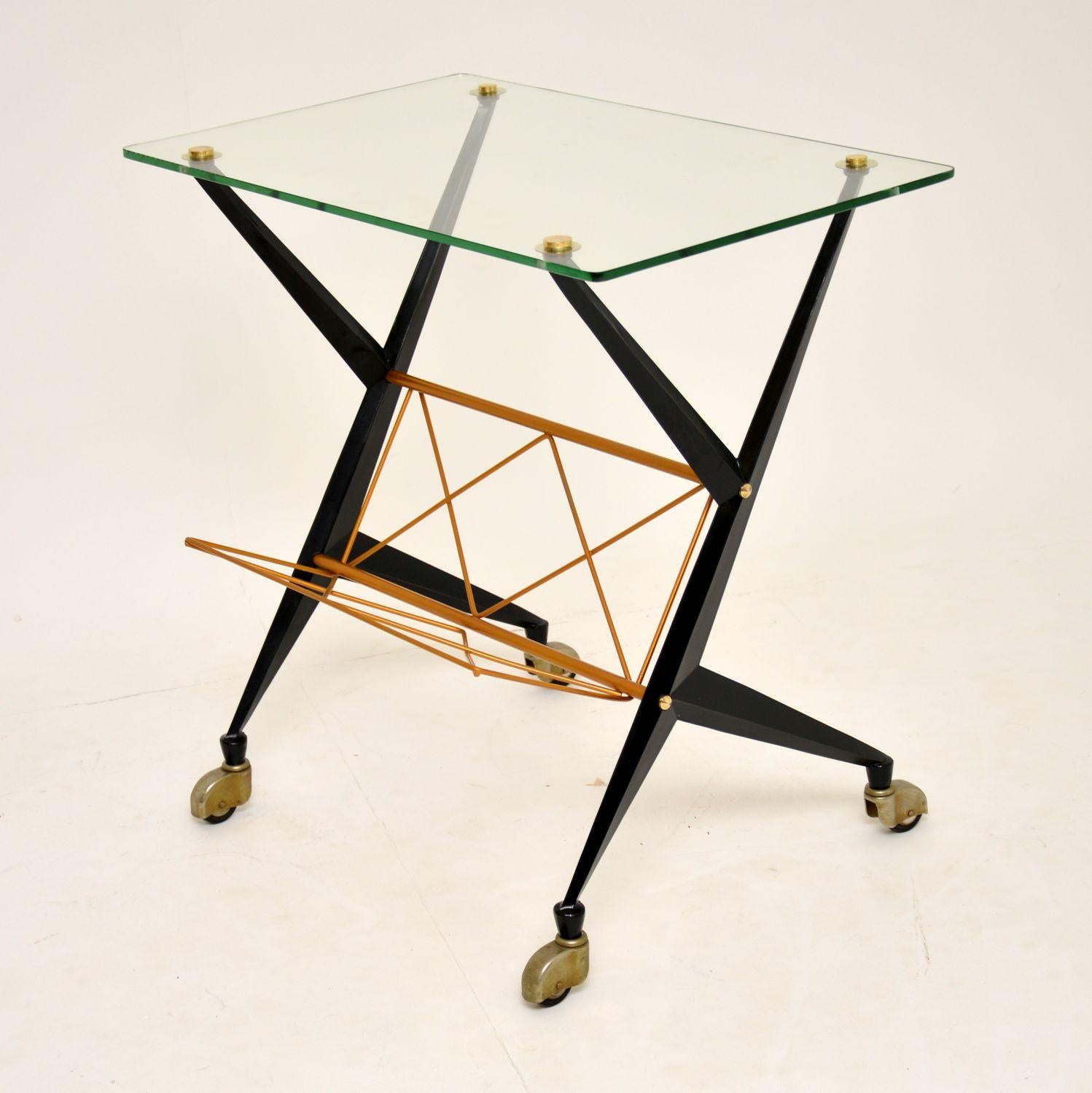 A stunning vintage Italian side table, designed by Angelo Ostuni for Frangi Milano. This dates from the 1960s-1970s, and is in superb condition for its age. The black lacquered metal frame has been and re-finished the gold magazine rack. The glass