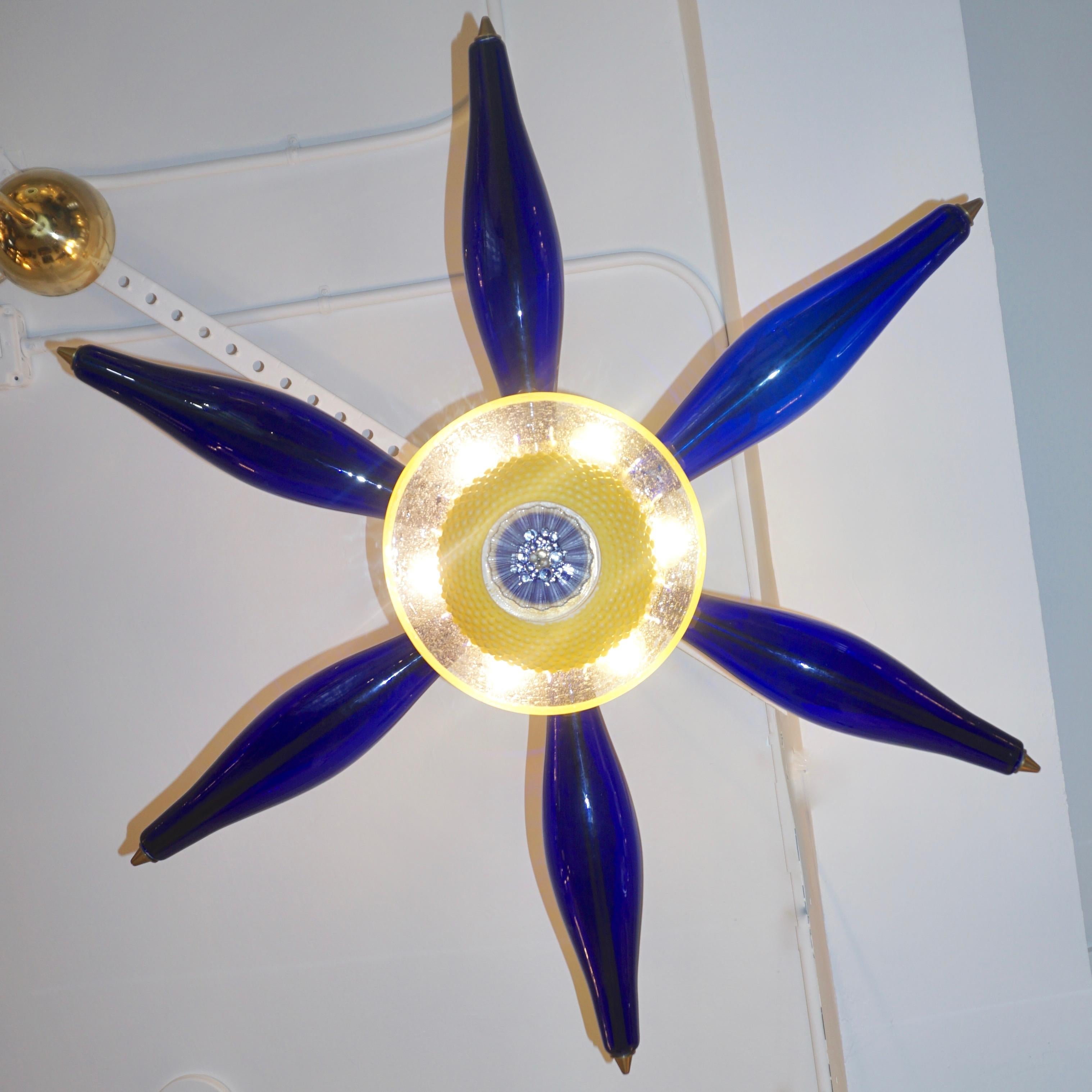 One-of-a-kind Italian design artistic pop art pendant, in the shape of a flower or six-point star. Six blown blue Murano glass elements, jutting out of a precious core consisting of rare yellow and clear Murano glass components executed through