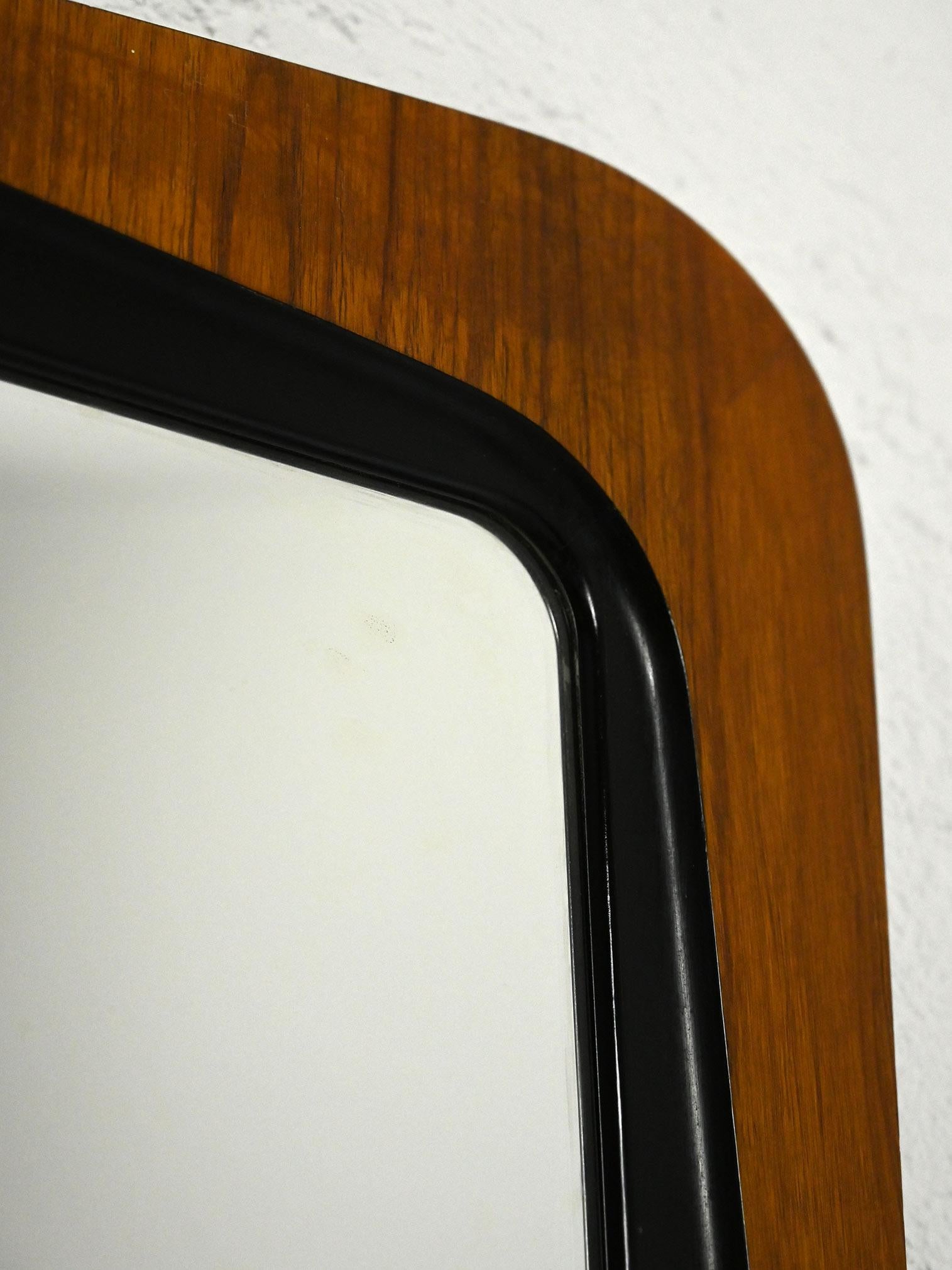 Scandinavian 1960s vintage mirror.

Vintage Scandinavian teak-framed mirror with a distinctive shape, slightly protruding, and small size. The distinctive detail of the frame is accentuated by a black outline around the mirror, adding a touch of