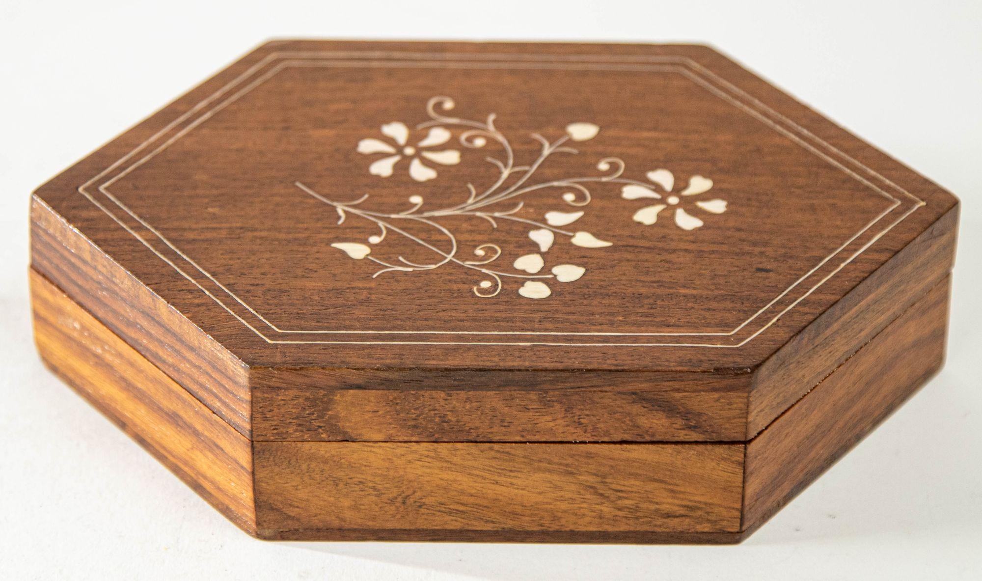 1960s Handcrafted Bone Inlaid Trinket Moroccan Wood Trinket Box.
Handgemachte handwerkliche Mitte Jahrhundert eingelegt Schmuckstück dekorativen Deckel marokkanischen Box.
Diese sechseckige, dekorative Schachtel hat eine komplizierte Blumenintarsie