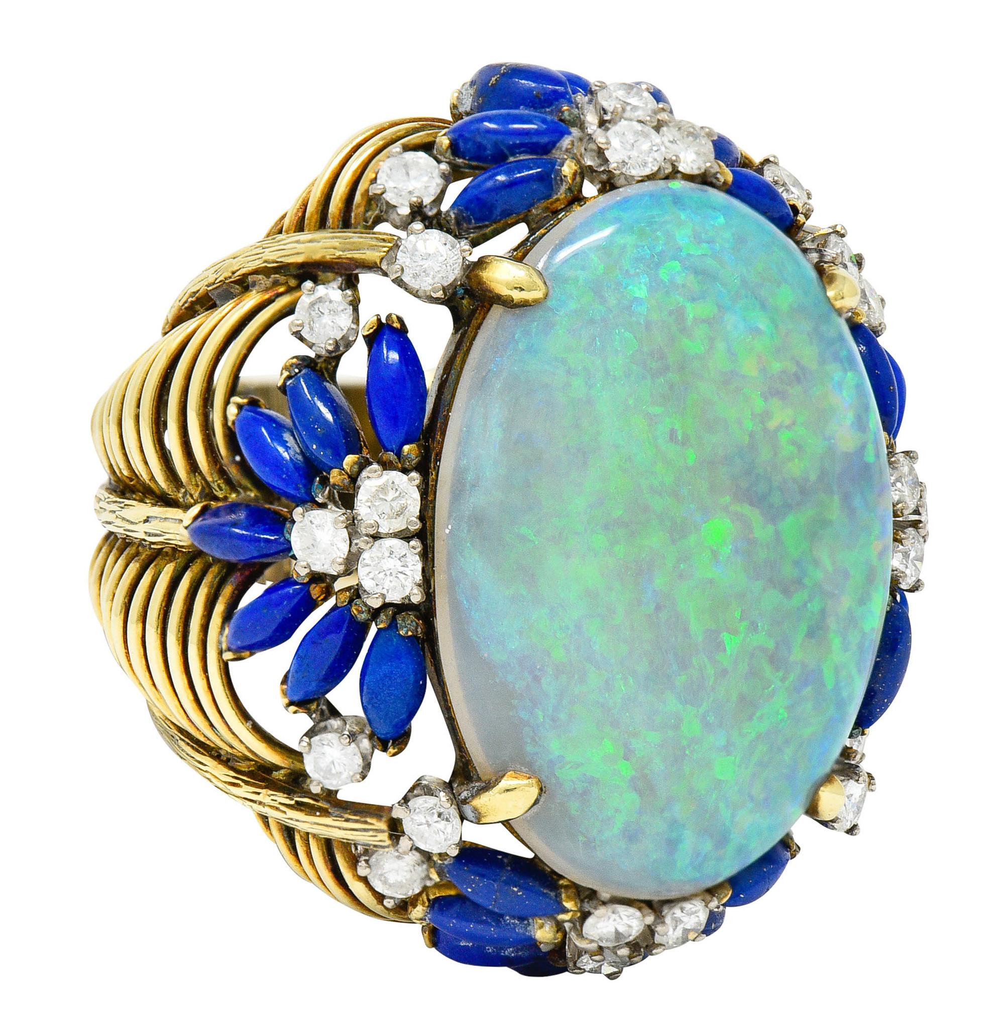 Substantial cluster ring is comprised of a swagged gold motif - deeply ridged

Centering an oval opal cabochon measuring approximately 25.5 x 18.0 mm

Translucent with very strong blue, green, and yellow play-of-color

With an ultramarine blue petal