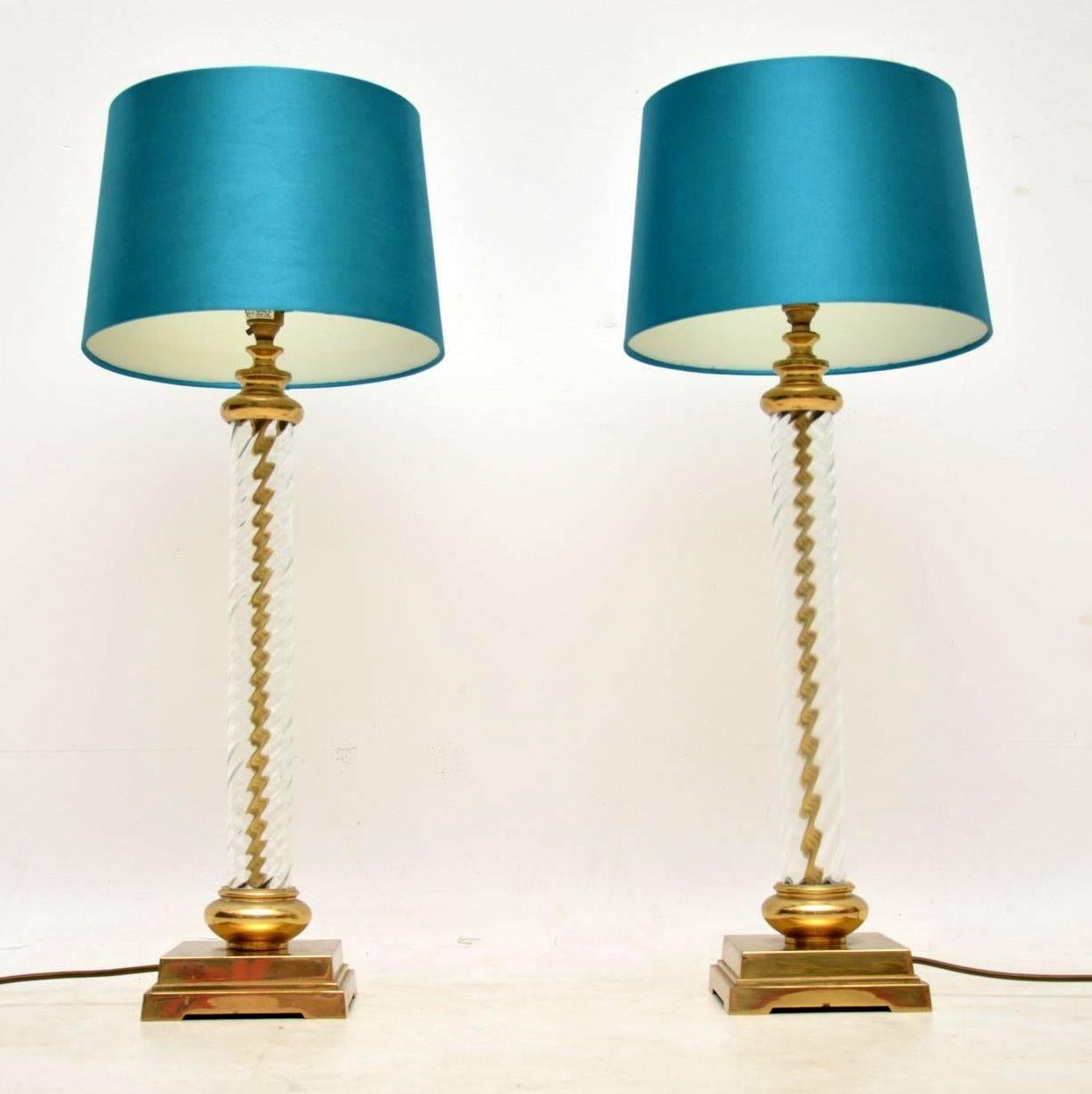 An absolutely stunning pair of vintage table lamps from the 1960s, these are in excellent condition for their age with only some minor wear here and there. They sit on brass bases, have a brass vertical column encased in swirling glass, with a brass