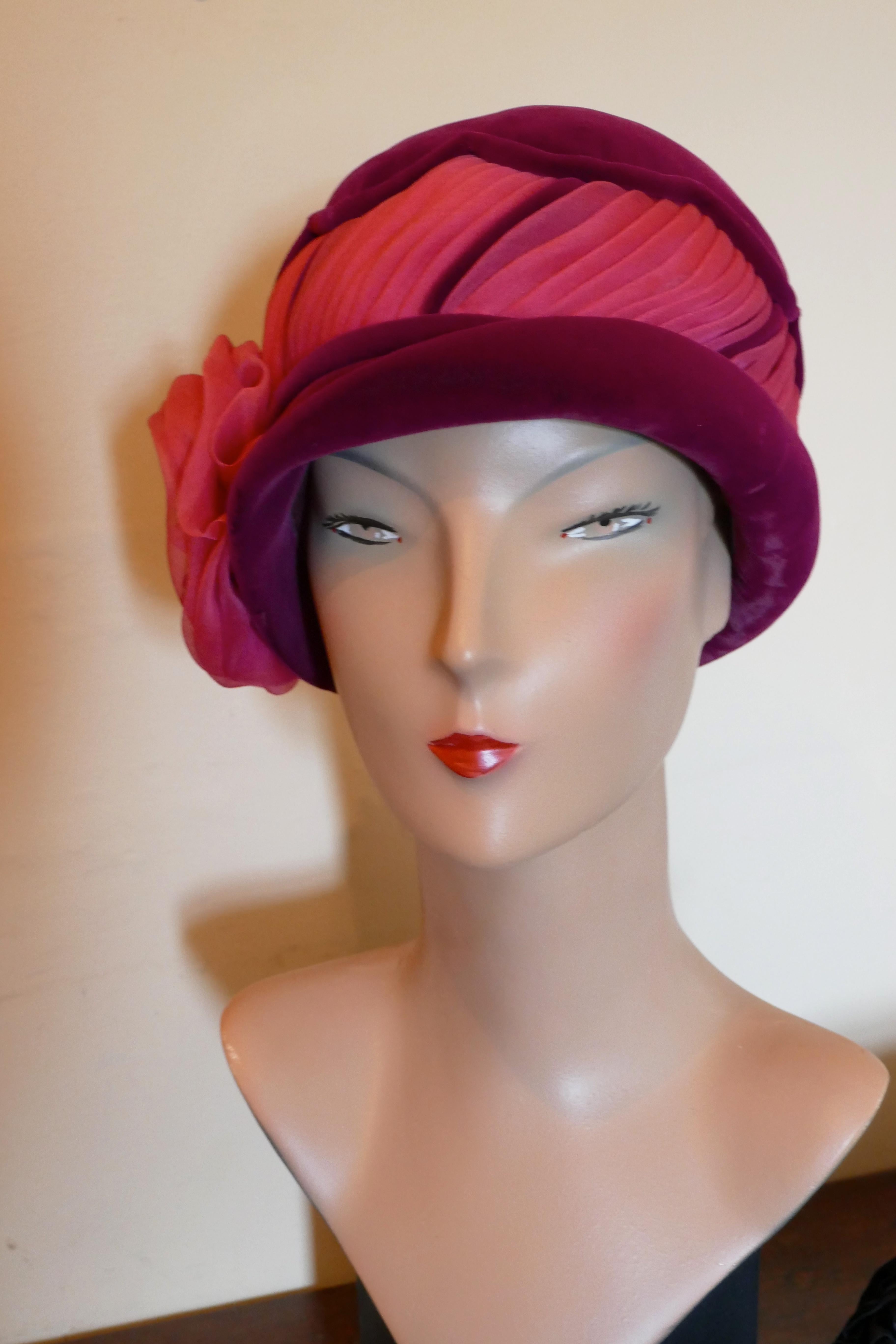 1960s Vintage Plush Velvet Cloche Hat by Mitzi Lorenz London W1

Superb Quality Plush Velvet Magenta Cloche hat with a deep gathered Cerise chiffon trim and a stunning chiffon rose to one side
The hat has a small rolled brim, it is satin lined, it