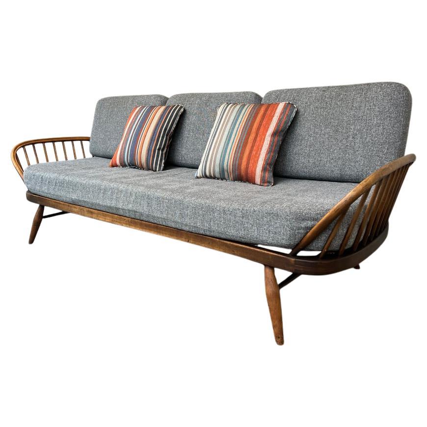 This Studio Couch is a charming and practical addition to any home. It is a nostalgic and standout. Featuring traditional spindle details and a simple, backrest created from a singular piece of carved surf board shaped wood. Arched steam-bent ash