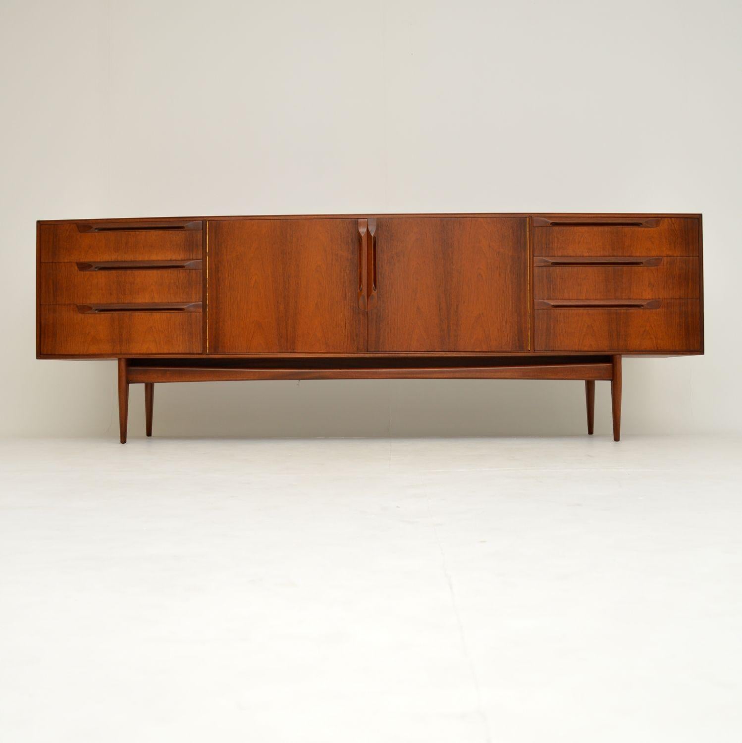 A stunning and very rare vintage sideboard. This was made by McIntosh, it dates from the 1960s. It is huge, and yet so sleek and stylish. The quality is incredible, and this is made from beautifully grained wood. The sculptural handles are a lovely