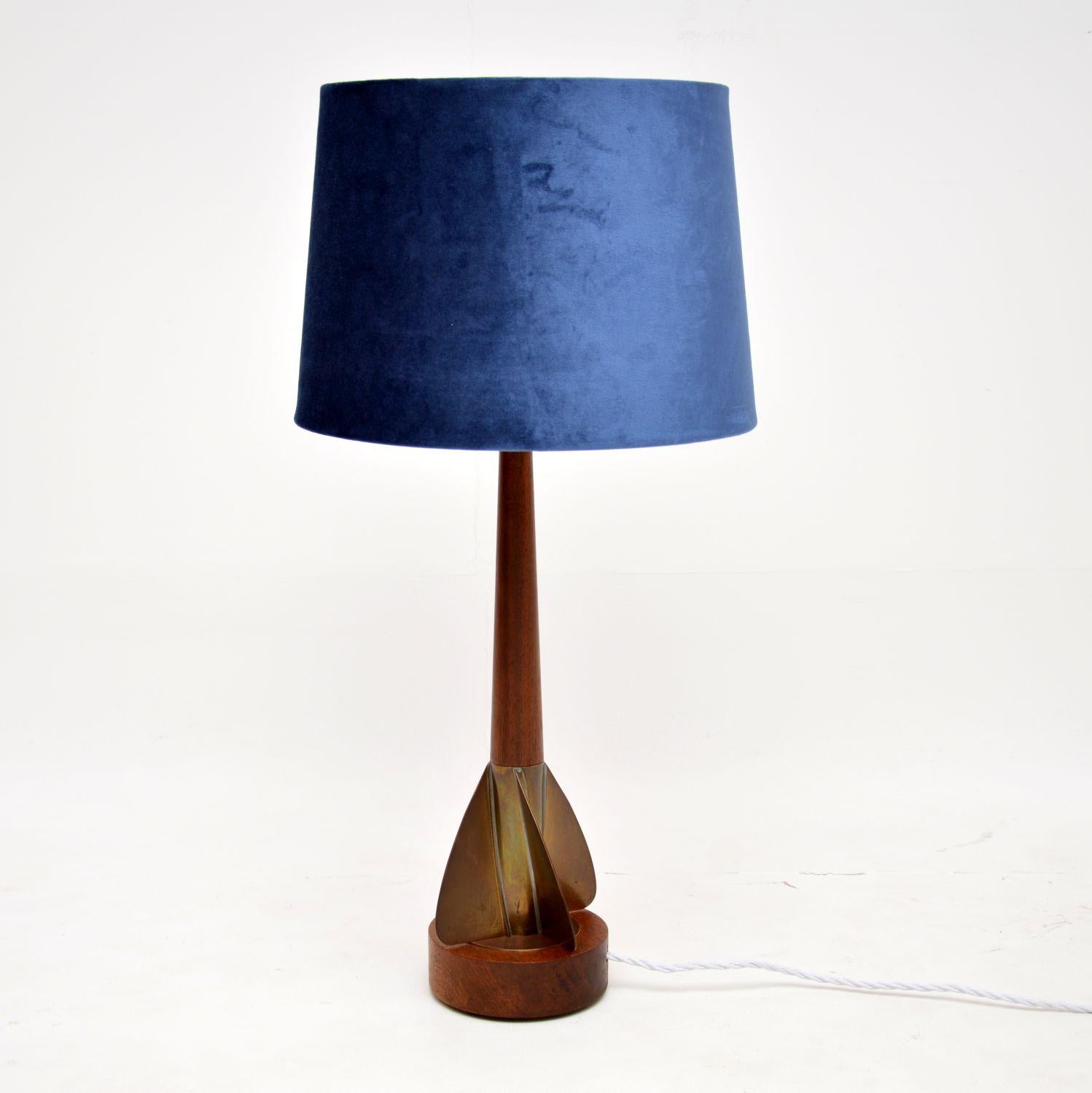 A very unusual and stylish vintage table lamp in solid teak and brass. This was made in England, it dates from the 1960’s.

It has an interesting brass propeller shaped base, this has the overall look and design of a rocket, reflecting the space