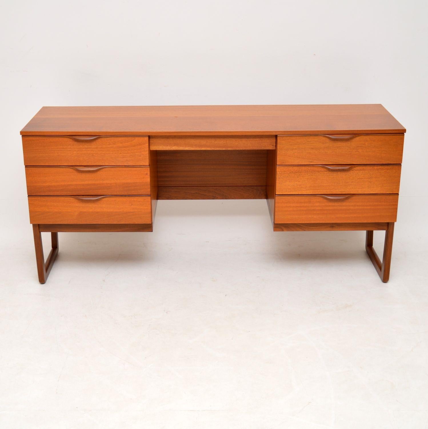 A stylish and well made vintage desk in teak, this dates from the 1960s. It has a beautiful design and is a very useful size, wide and not too deep, with plenty of storage space and a generous knee hole. We have had this stripped and re-polished to