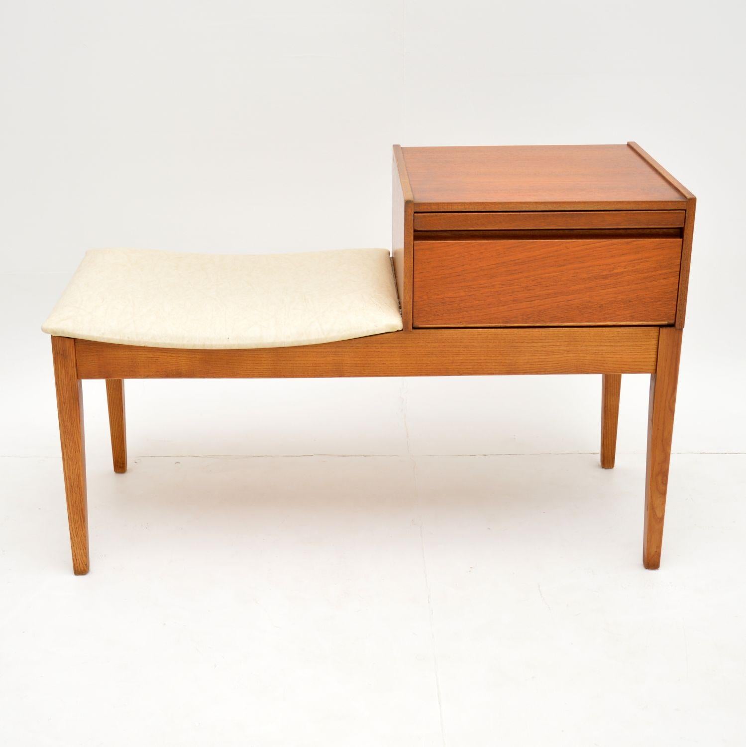 A stylish and beautifully made telephone entry way bench in teak. This dates from the 1960s, and is in lovely original condition. We have just given the teak frame a light clean and oiling. It is sturdy and sound, the original cream vinyl seat is in