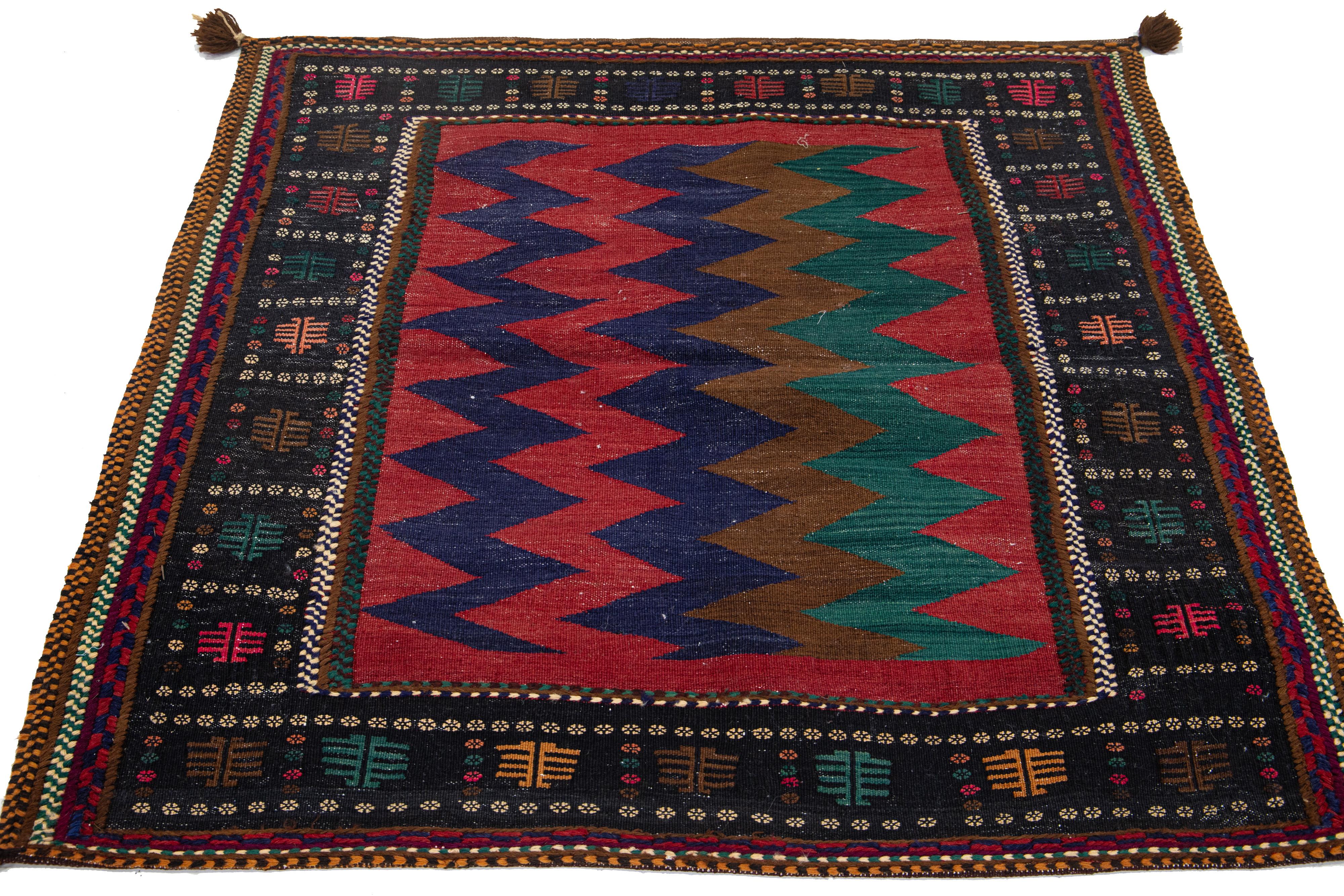 This Persian Shiraz wool rug displays an elaborate tribal design featuring stunning green, blue, and brown accents on a red background.

This rug measures 3'11