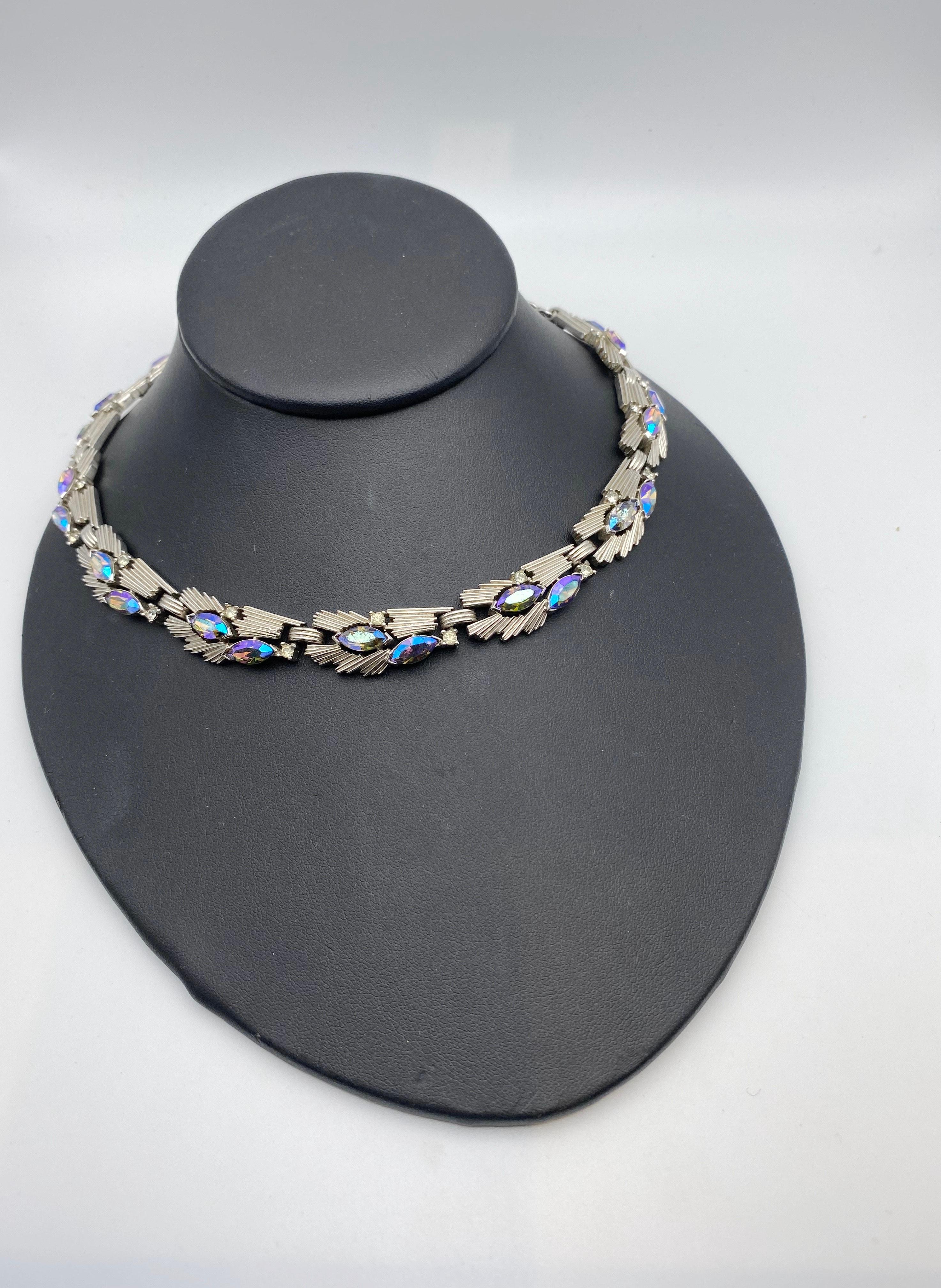 Un superbe collier Trifari de style moderniste, extrêmement rare à trouver. Les bijoux sont en argenté texturé, avec des navettes Aurora Borealis et des cristaux à multiples facettes. Une excellente pièce pour marquer une occasion spéciale ou pour