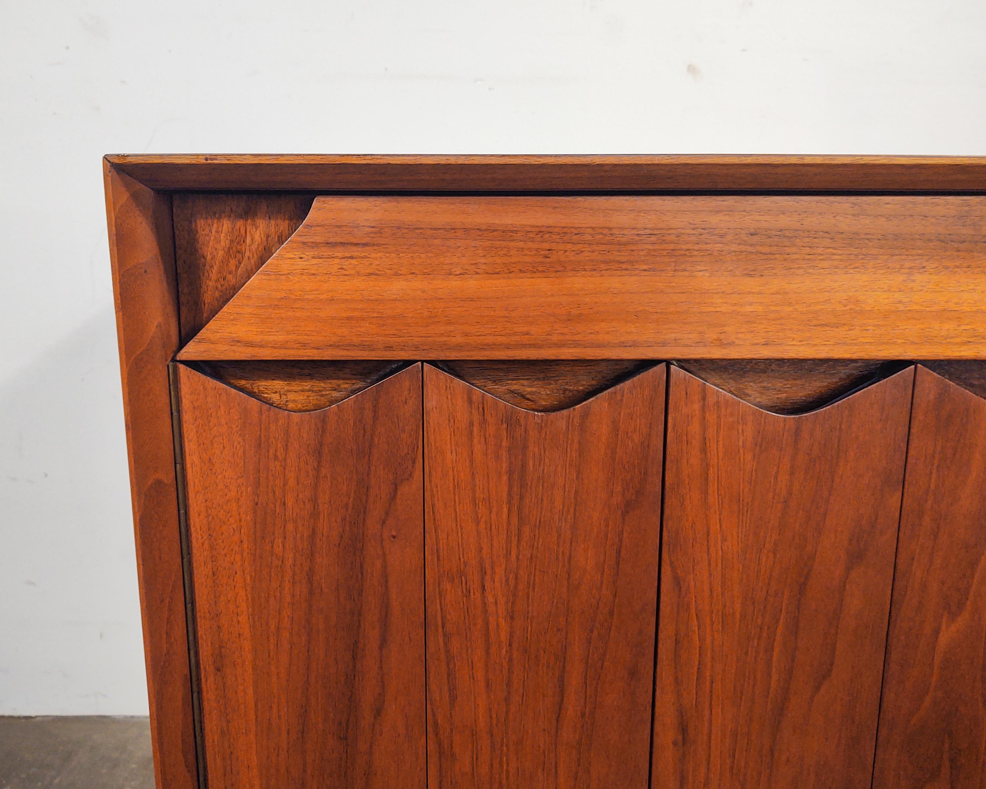 Rare walnut nightstand cabinet designed by Marc Berge for Grosfeld House circa 1960s. Unique design featuring geometric lines. Shallow drawer on top and bifold cabinet below with removable shelf. Excellent craftsmanship with solid wood construction
