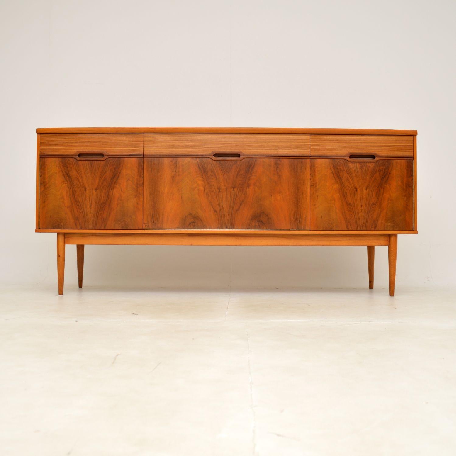 A very stylish and extremely well made vintage sideboard in walnut. This was made in England, it dates from the 1960s.
The quality is outstanding, this is very well constructed and has a beautiful design. It sits on finely tapered legs, with