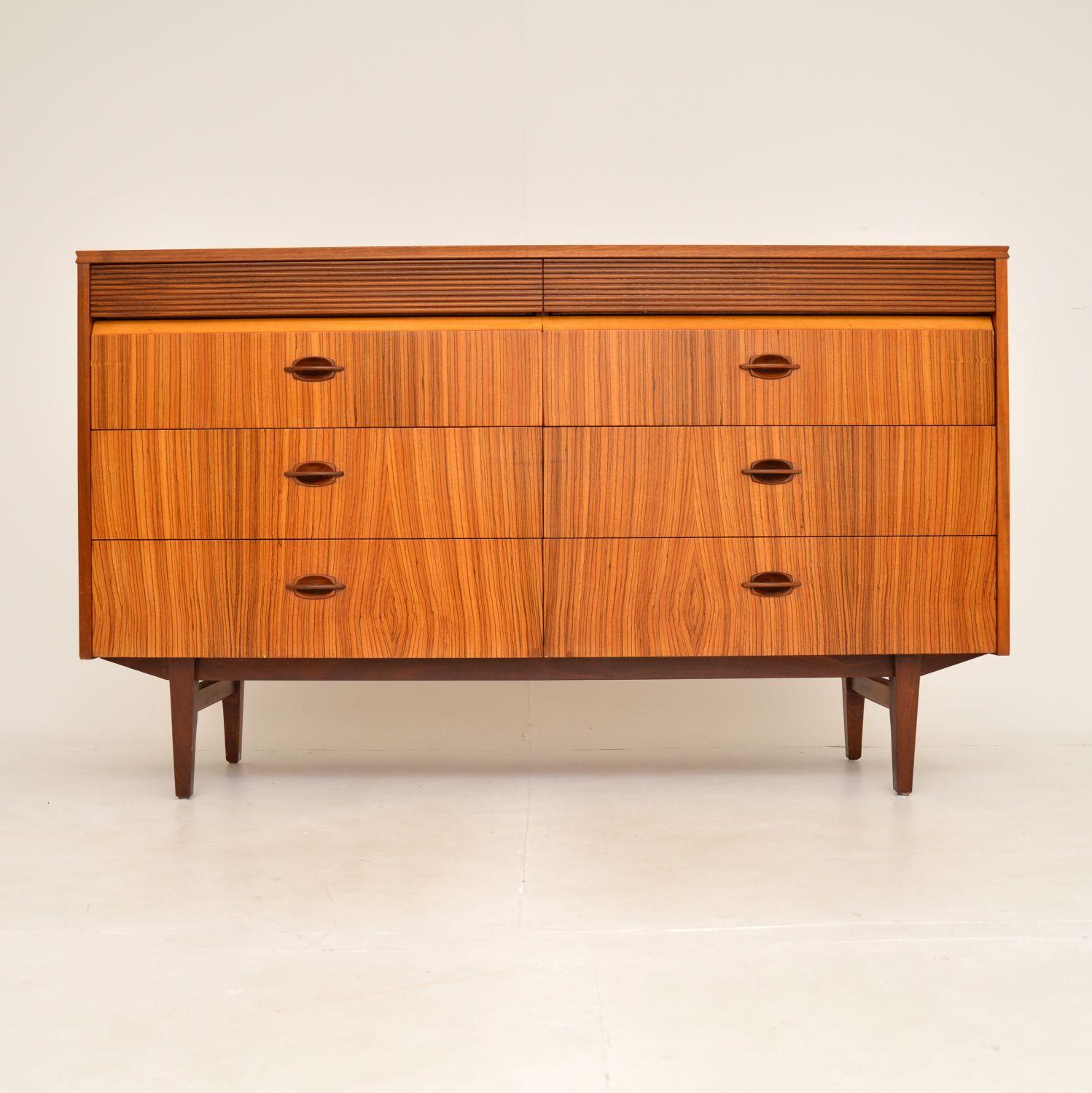 A stunning vintage sideboard / chest of drawers dating from the 1960’s. This was made in England by the high end manufacturer Elliot’s of Newbury.

The lower drawer fronts are made from striking Zebrano wood, the top and sides are Walnut. The top