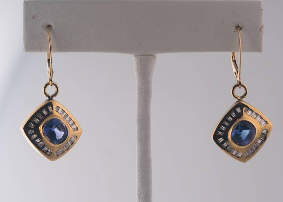 1960s Retro Drop Earrings - 14 Karat Yellow Gold, Blue Violet Tanzanite, Diamonds

Features a Gorgeous bezel set Blue Violet Tanzanite center stone. Each 1.5 carat Tanzanite is framed by a Baguette Diamond Halo in a 14 karat yellow Gold frame. The