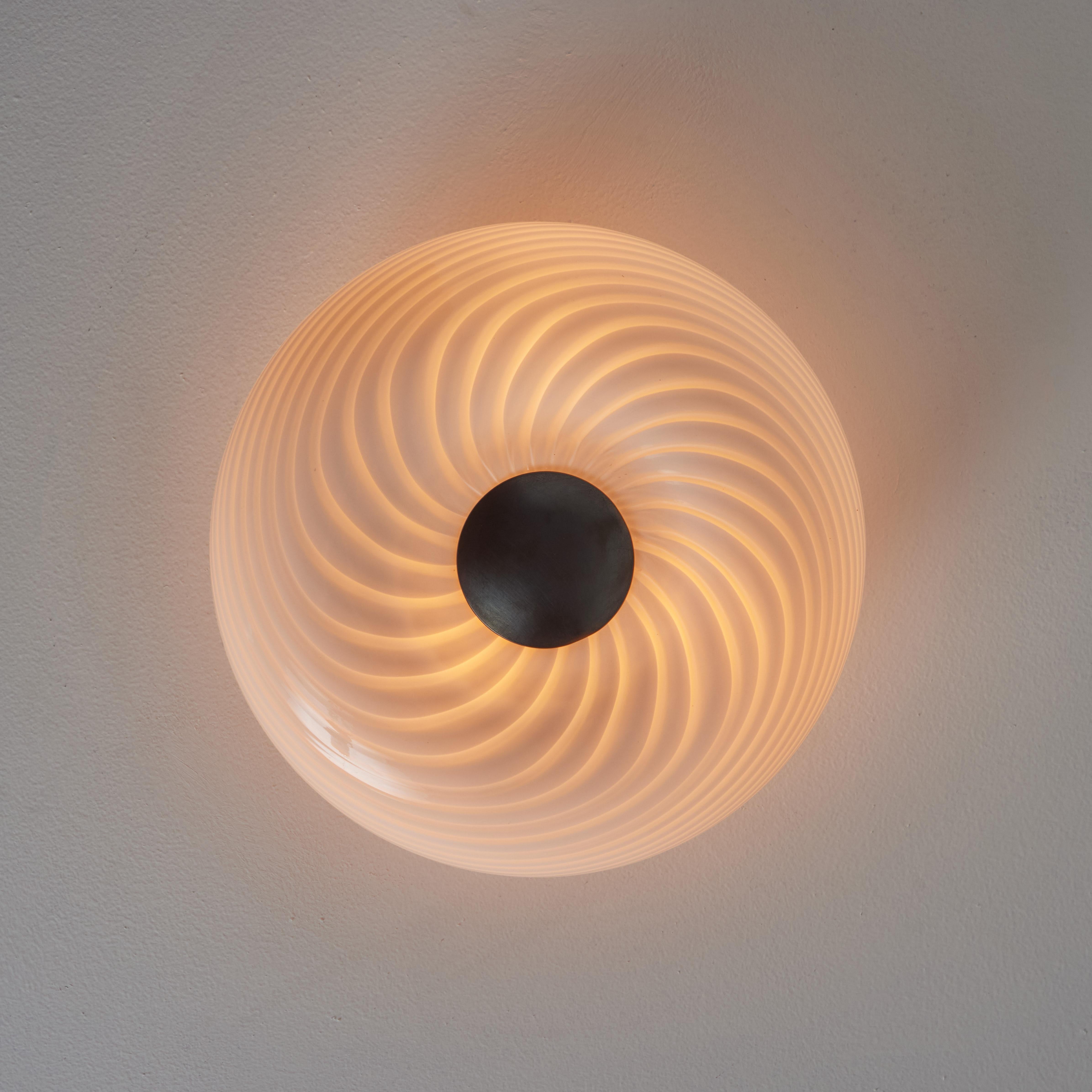 1960s Vistosi Blown Murano Glass Wall or Ceiling Light.

Executed in blown Murano glass with a patinated brass centerpiece, this rare flush mount features a distinctive spiral pattern and can be installed on either the wall or the ceiling. Its