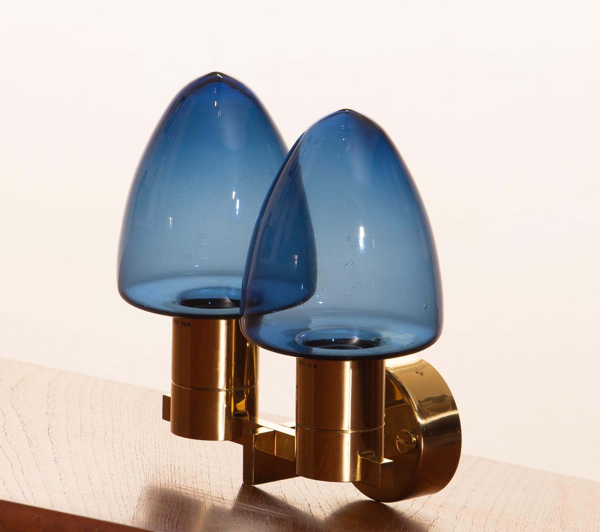 Beautiful wall light/sconce with two blue glass shades by Hans-Anne Jakobsson for Markaryd 1960.
This wall light is, except a hairline on the back plate, in good condition. 
Technically 100%.
Including mounting plate and original